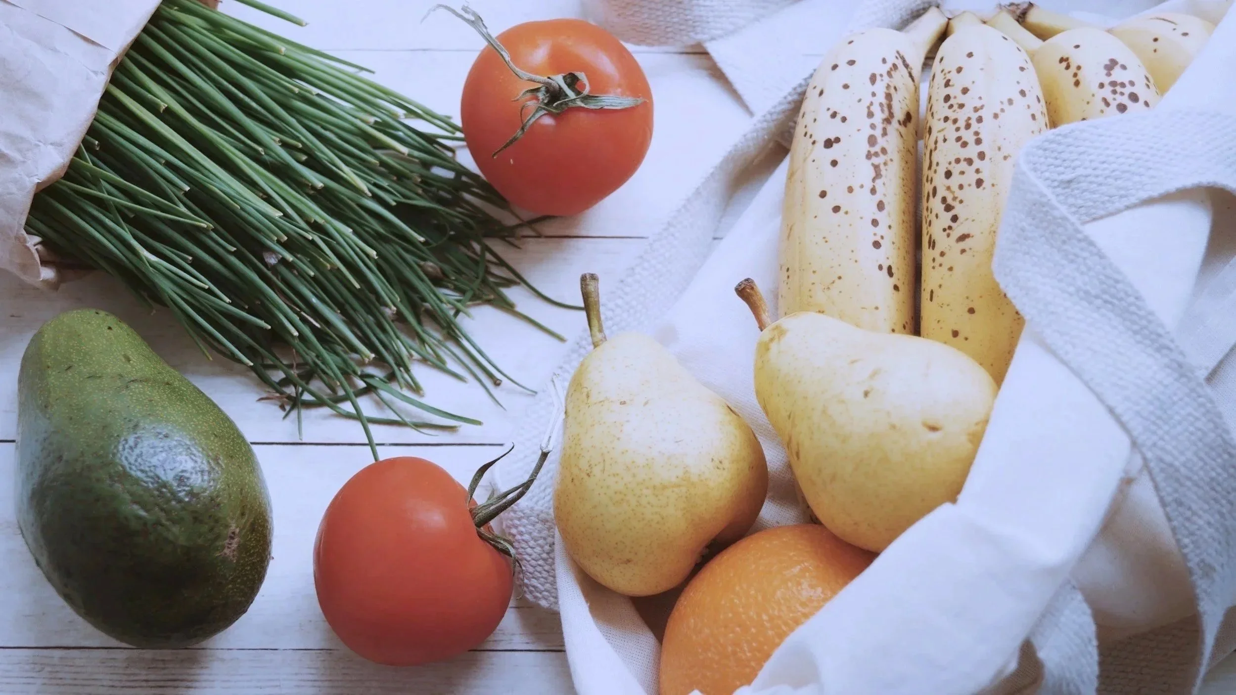 Groceries on a table peeking out of a shopping bag.