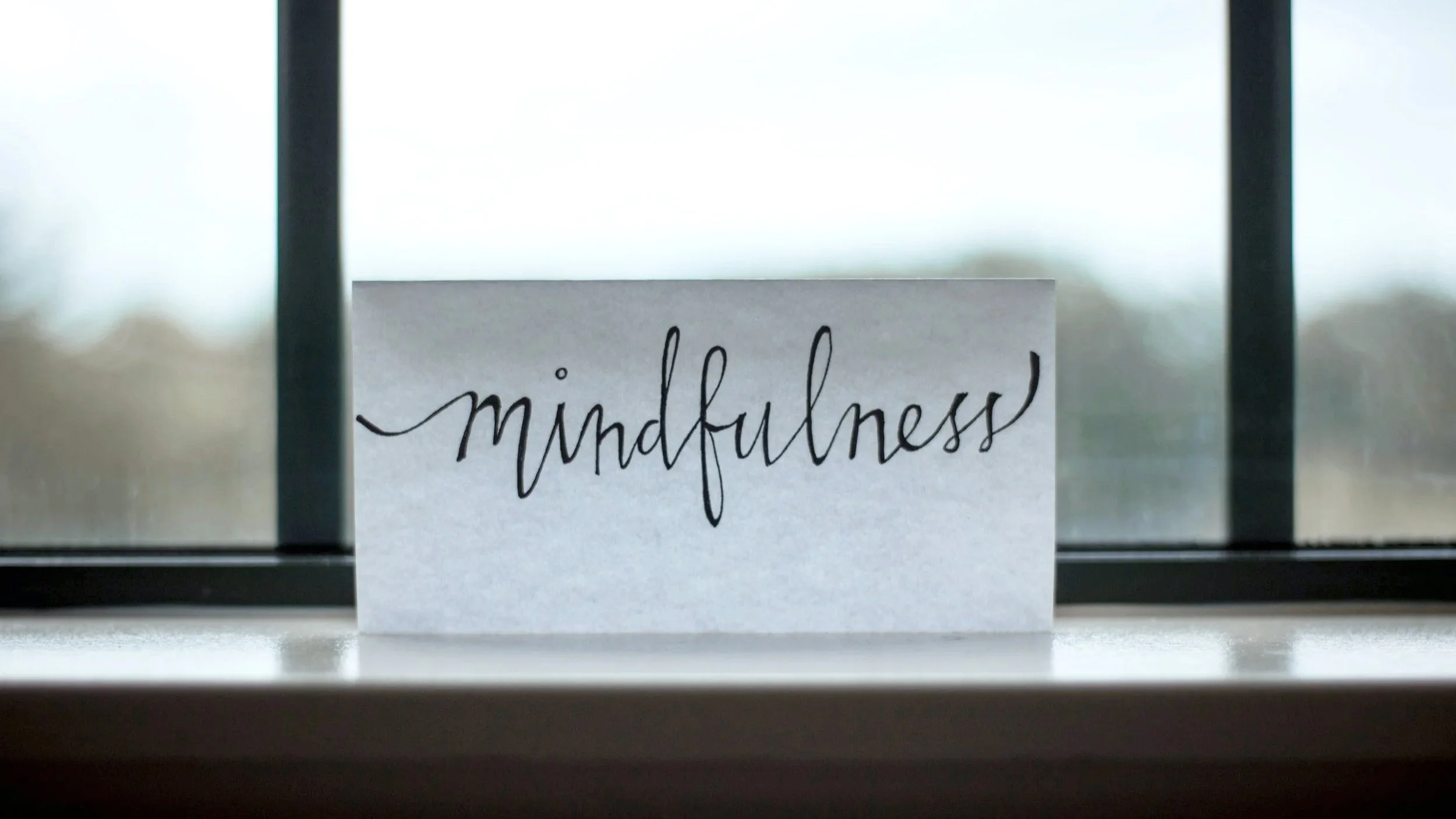 the word mindfulness written on a piece of paper in front of a window.