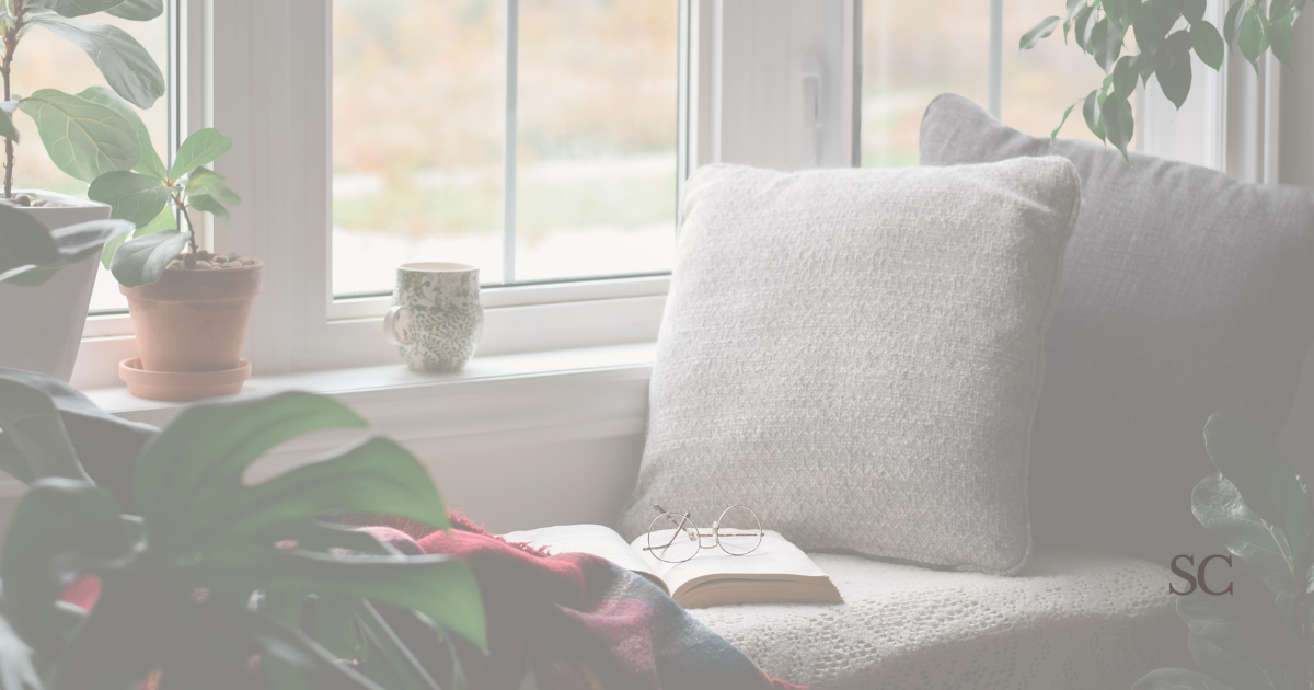 book with glasses on top of a window seat, depicting a cozy relaxing moment.
