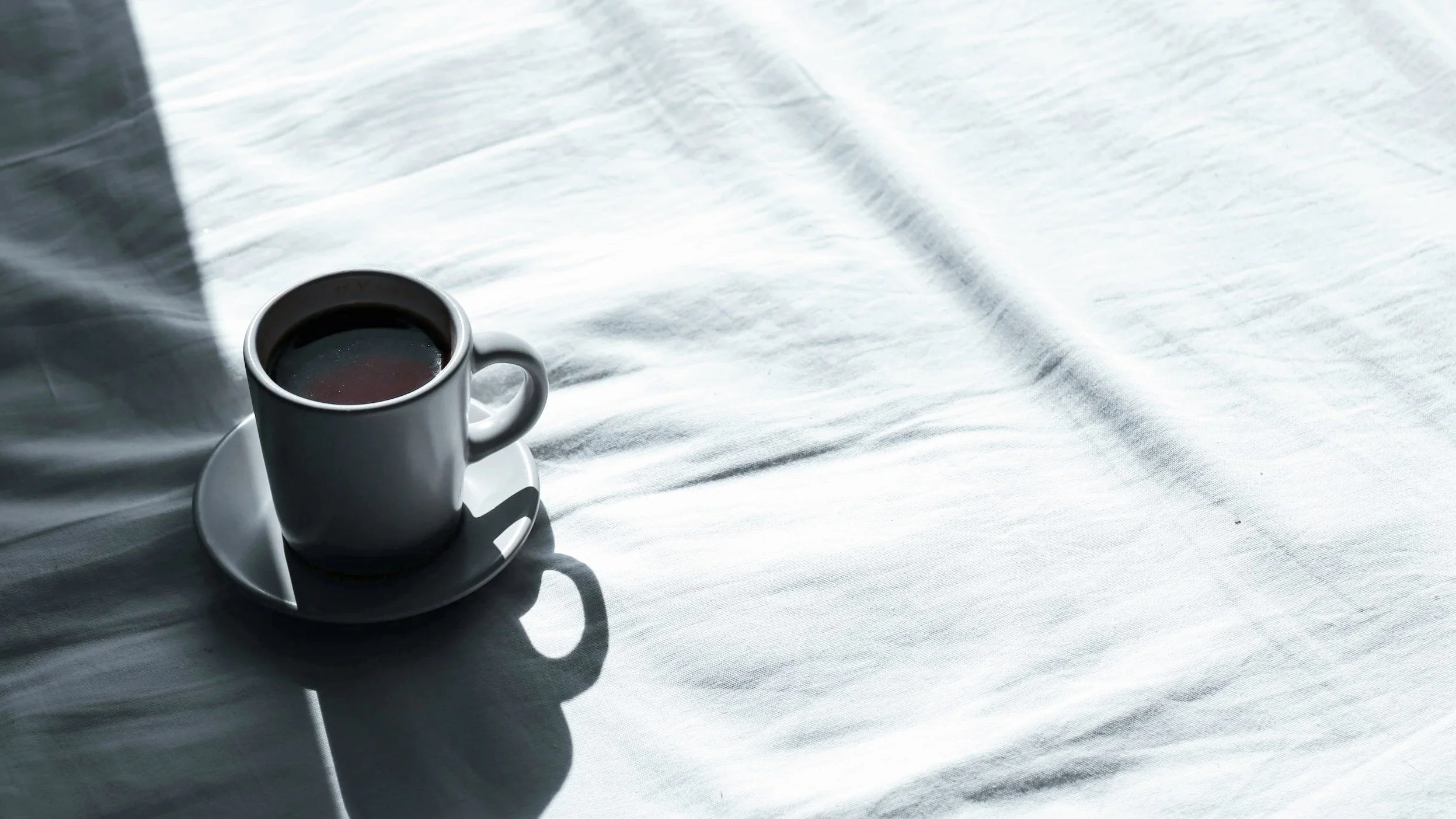 Coffee cup on bed symbolising contemplation of Atomic Habits and how to Habit Stack in Daily Life