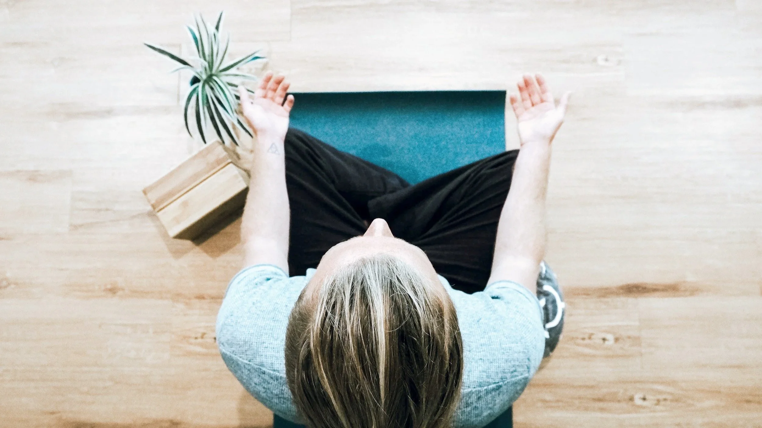 Image from top down long at a person sitting on a mat meditating