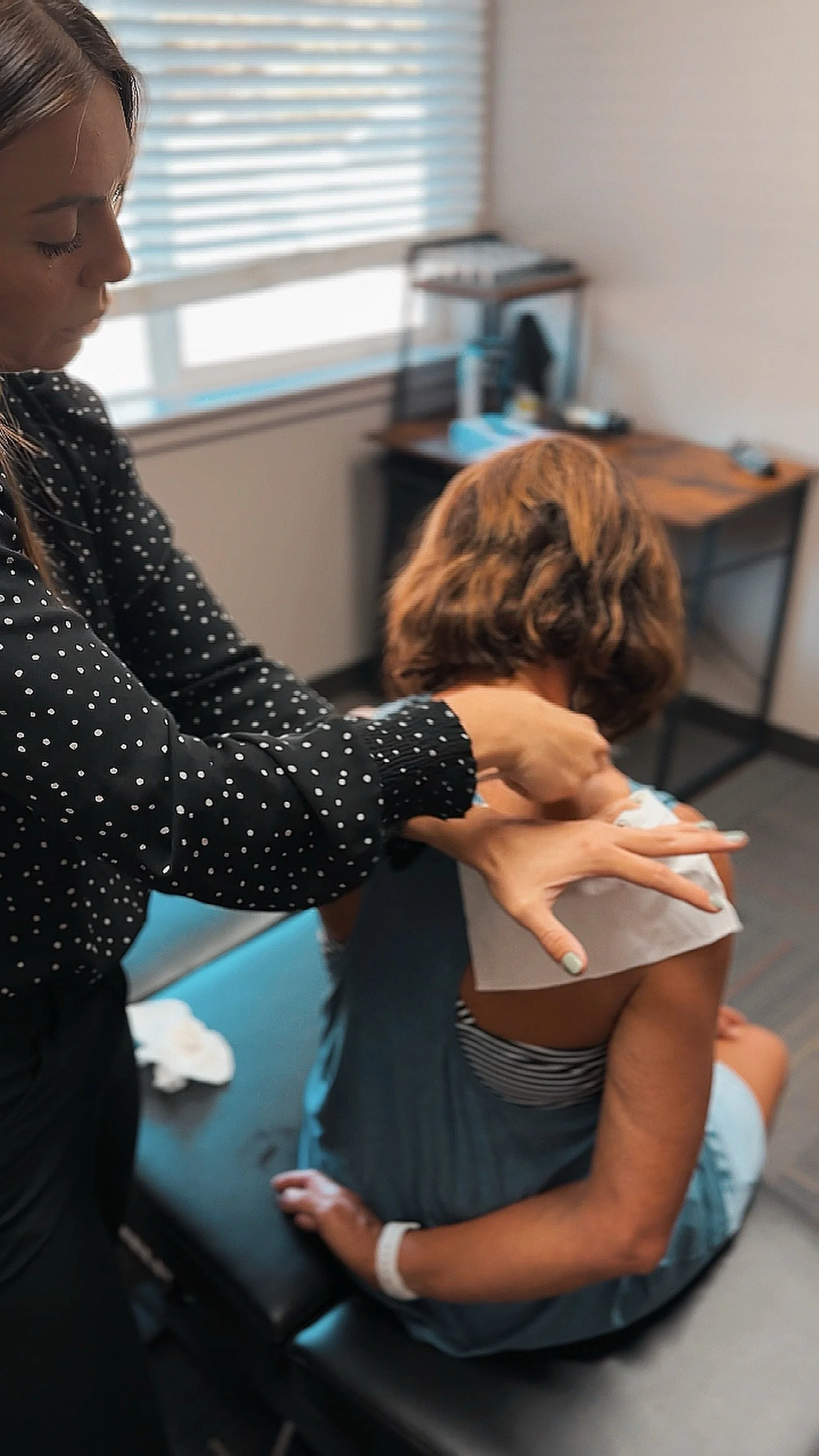 Doctor using hands-on soft tissue therapies to help with neck pain on a female patient