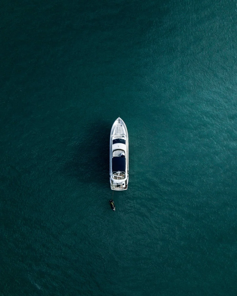 Aerial view of a white luxury yacht in deep blue water, establishing scale and exclusivity.