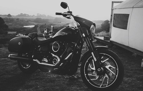 A classic motorcycle parked outdoors, presented in black and white.