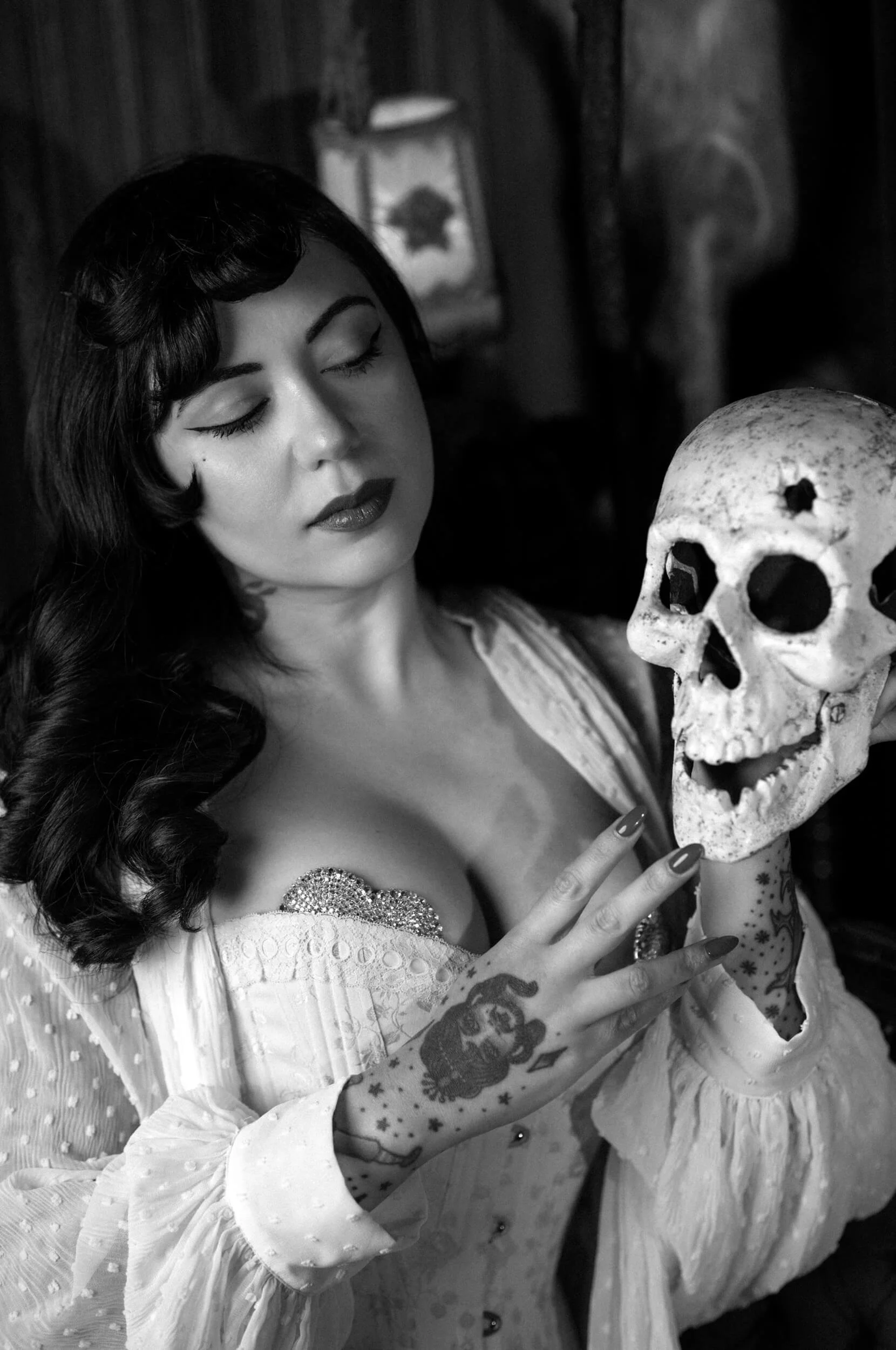 Black-and-white portrait of Bettie From Hell holding a skull, photographed with the Thypoch Simera 75mm f/1.4 on the Leica M11 Monochrom.