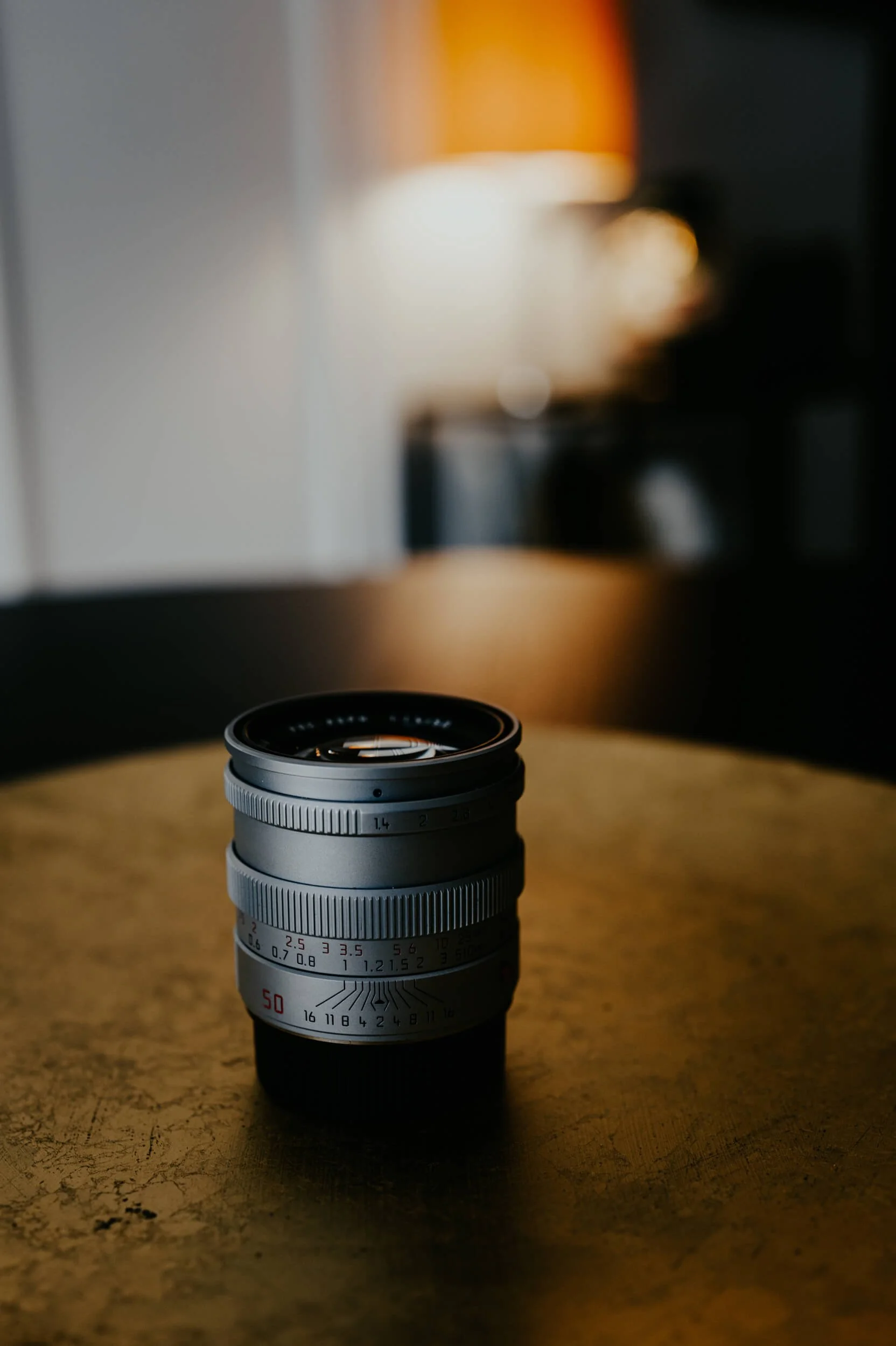 Mandler 50mm f/1.4 E46 Pre-A lens in brass finish, photographed in warm cinematic light.