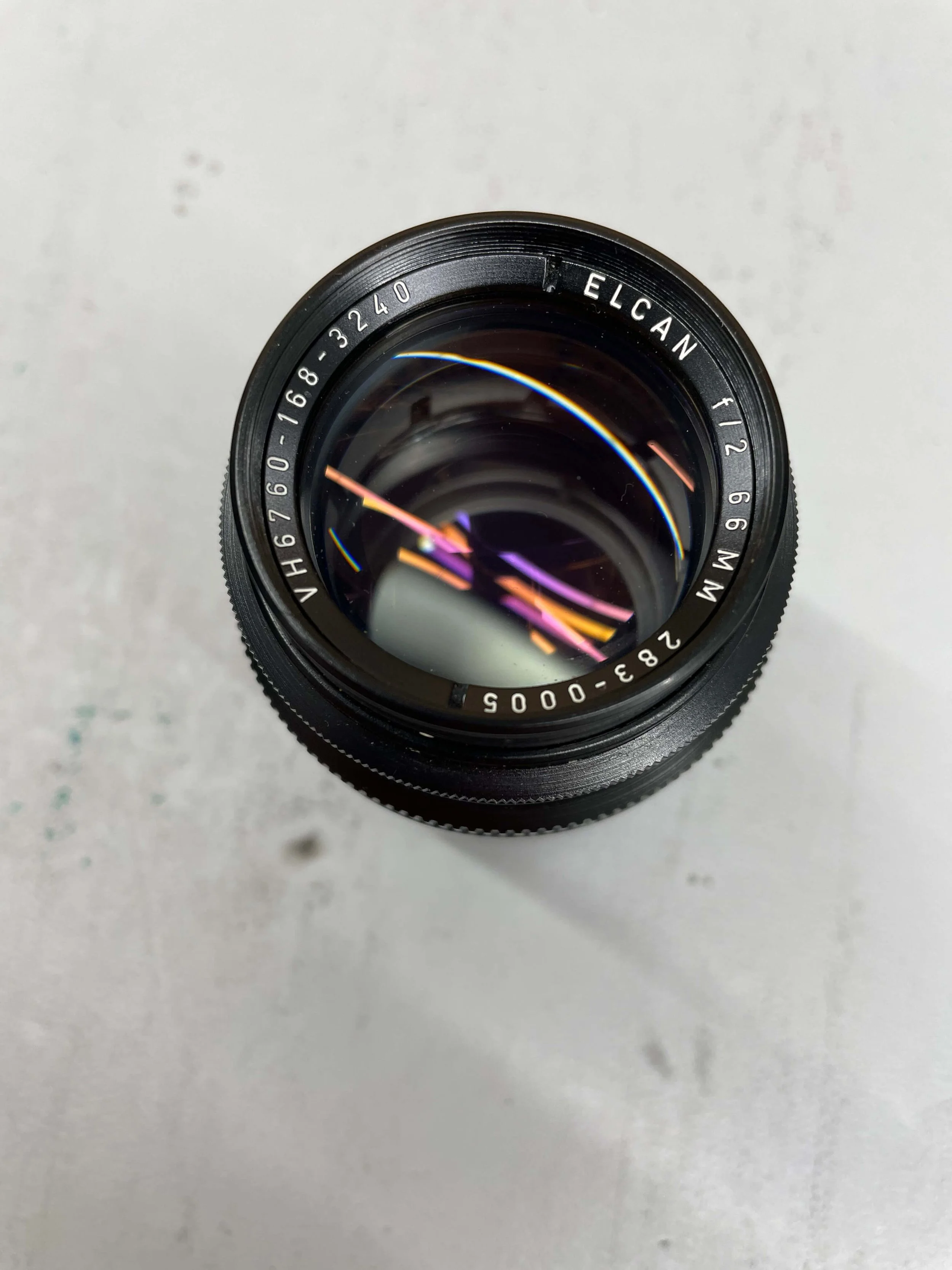 Close-up of the original ELCAN 66mm f/2 showing its front element, coatings and engraved lens markings.