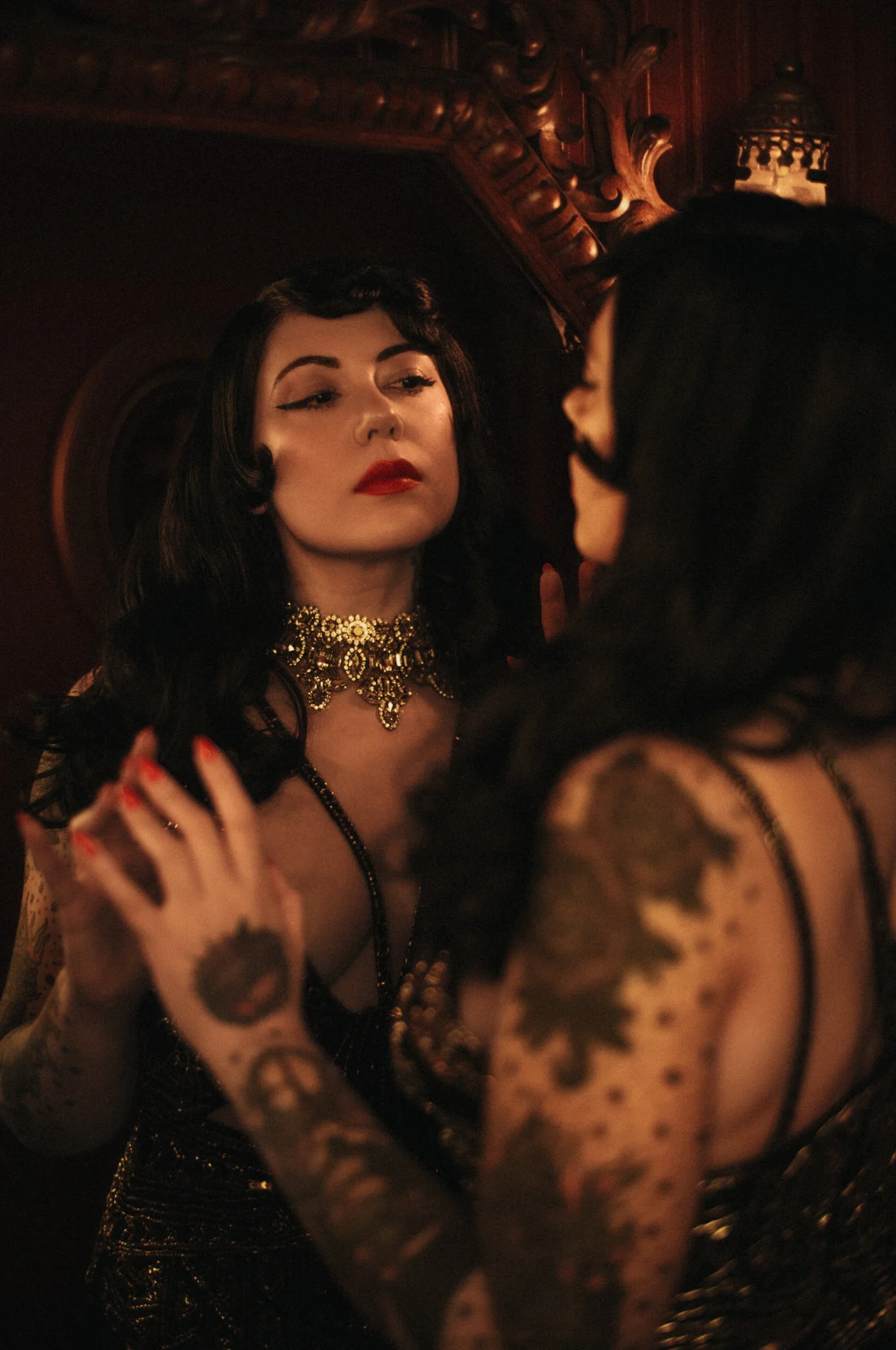 Cinematic portrait of Bettie from Hell wearing a black evening dress and gold jewellery, photographed with the Mandler 50mm f/1.4 E46 Pre-A lens.