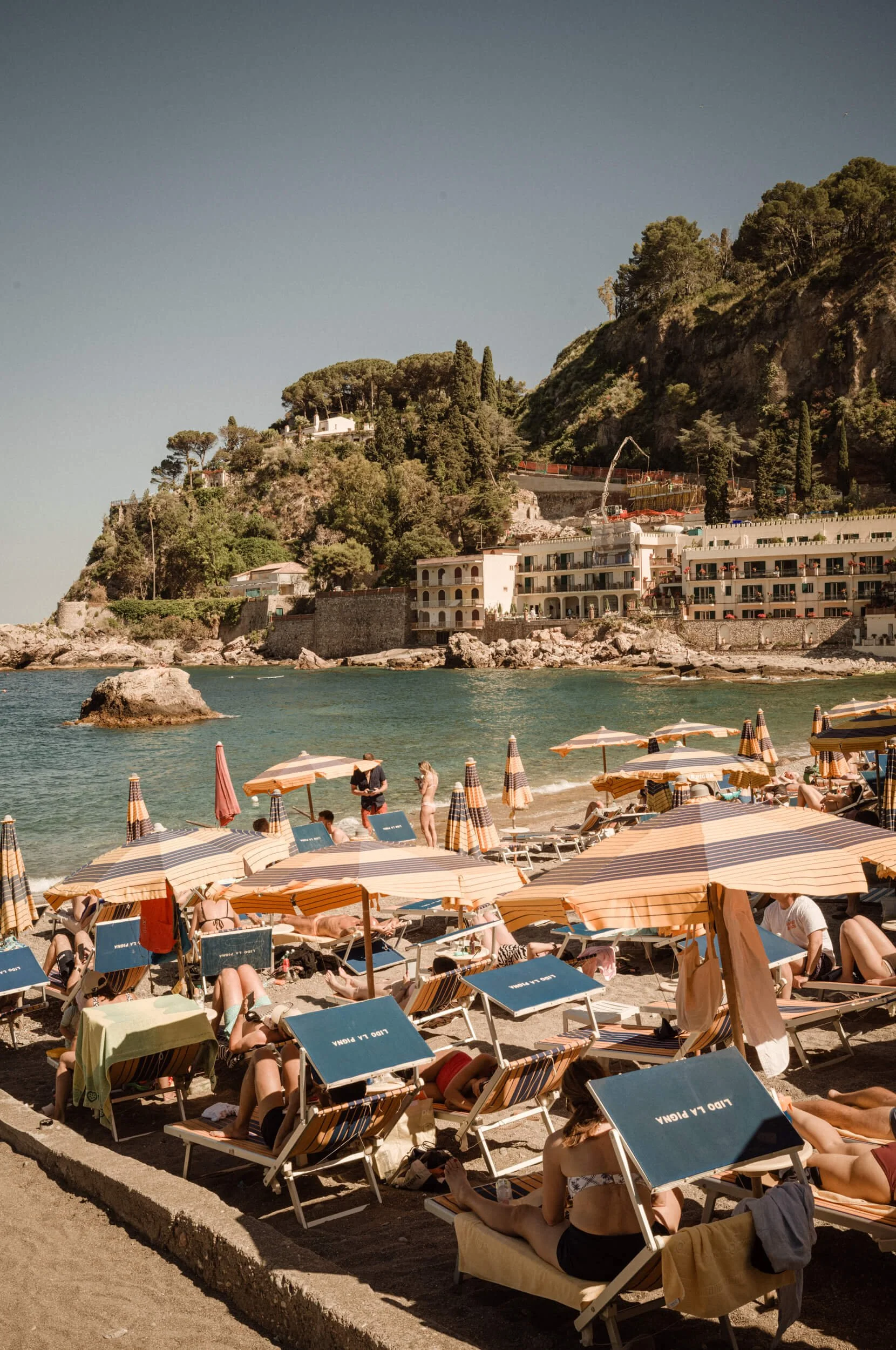 Beach umbrellas and visitors on a beach in Taormina, Sicily, photographed with the Thypoch Ksana 35mm f/2.