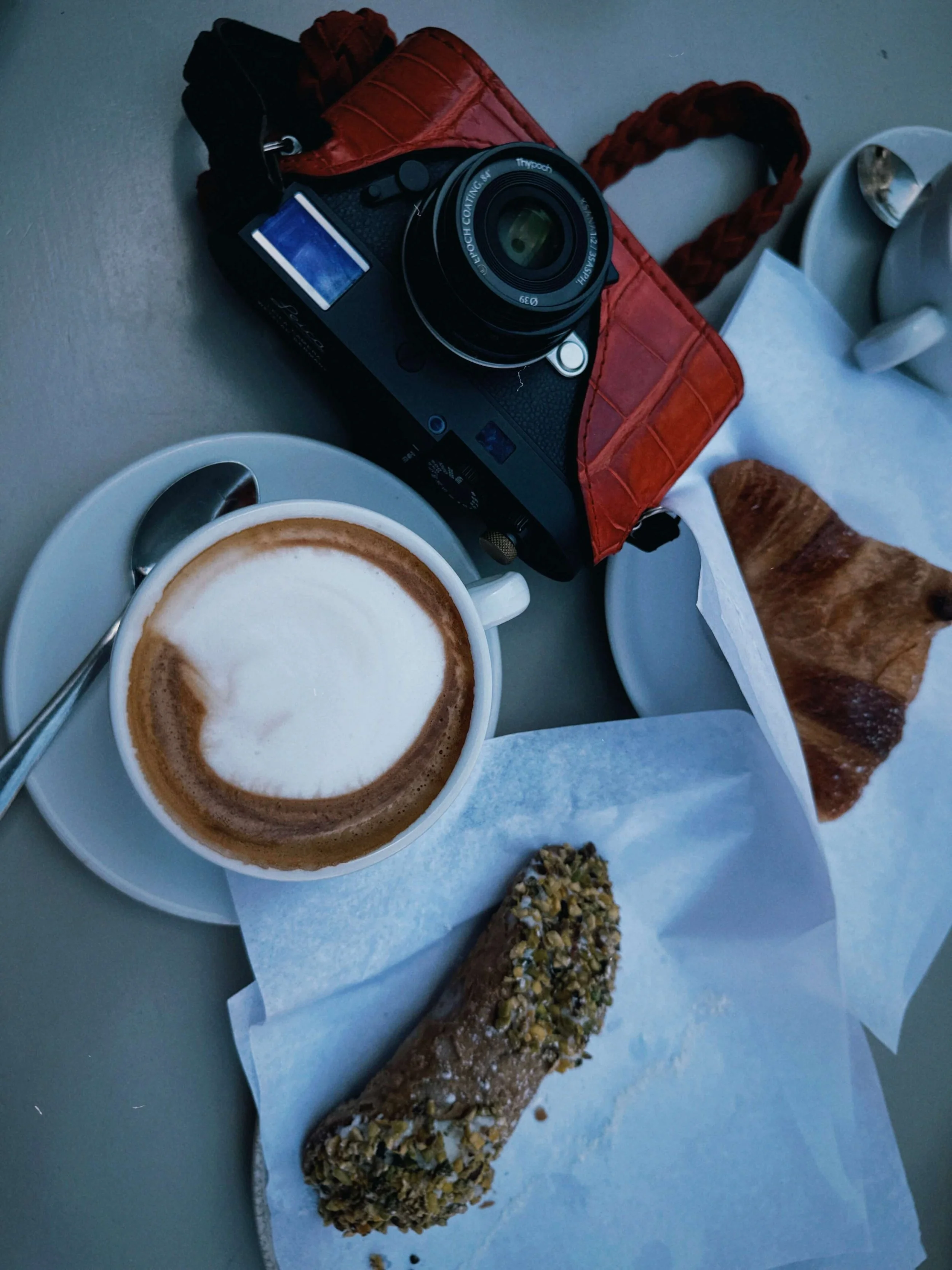 Leica M11-D with Thypoch Ksana 35mm f/2 beside coffee and Sicilian pastries during a travel photography break in Sicily