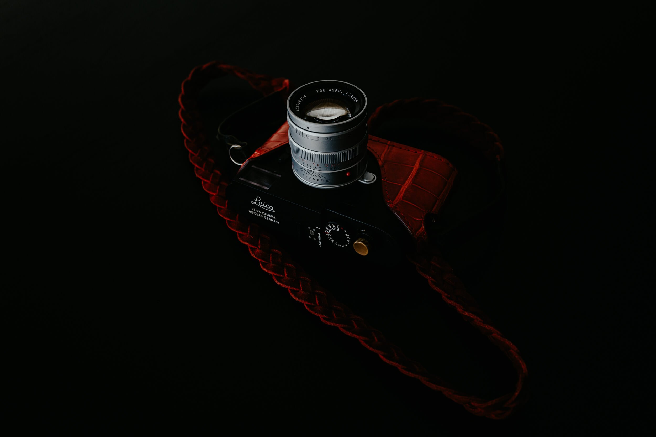 Brass Mandler 50mm f/1.4 E46 Pre-A lens mounted on the Leica M11-D with a red leather camera case by Angelo Pelle.