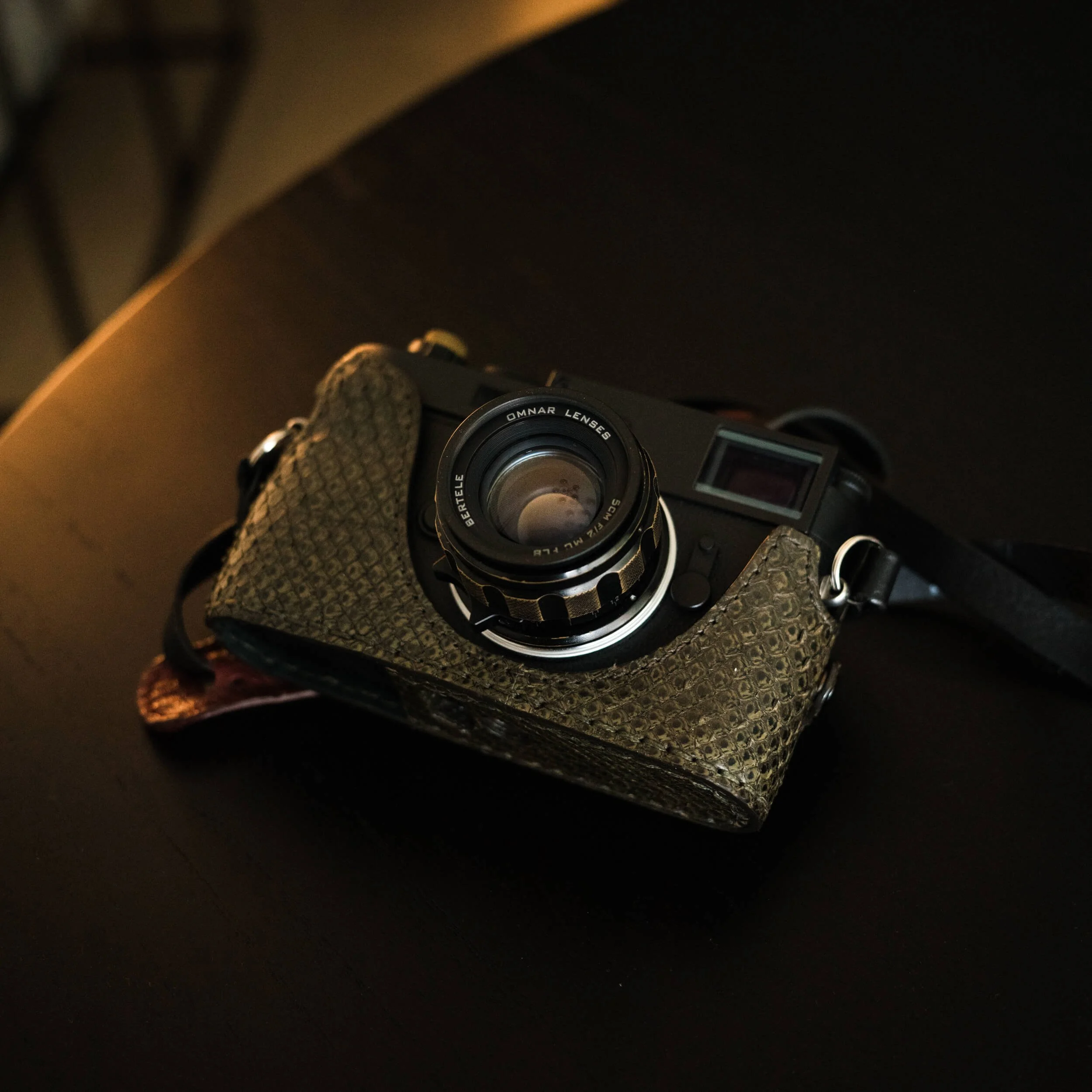 Omnar Bertele 50mm f/2 mounted on a Leica M11 Monochrom resting on a dark wooden table
