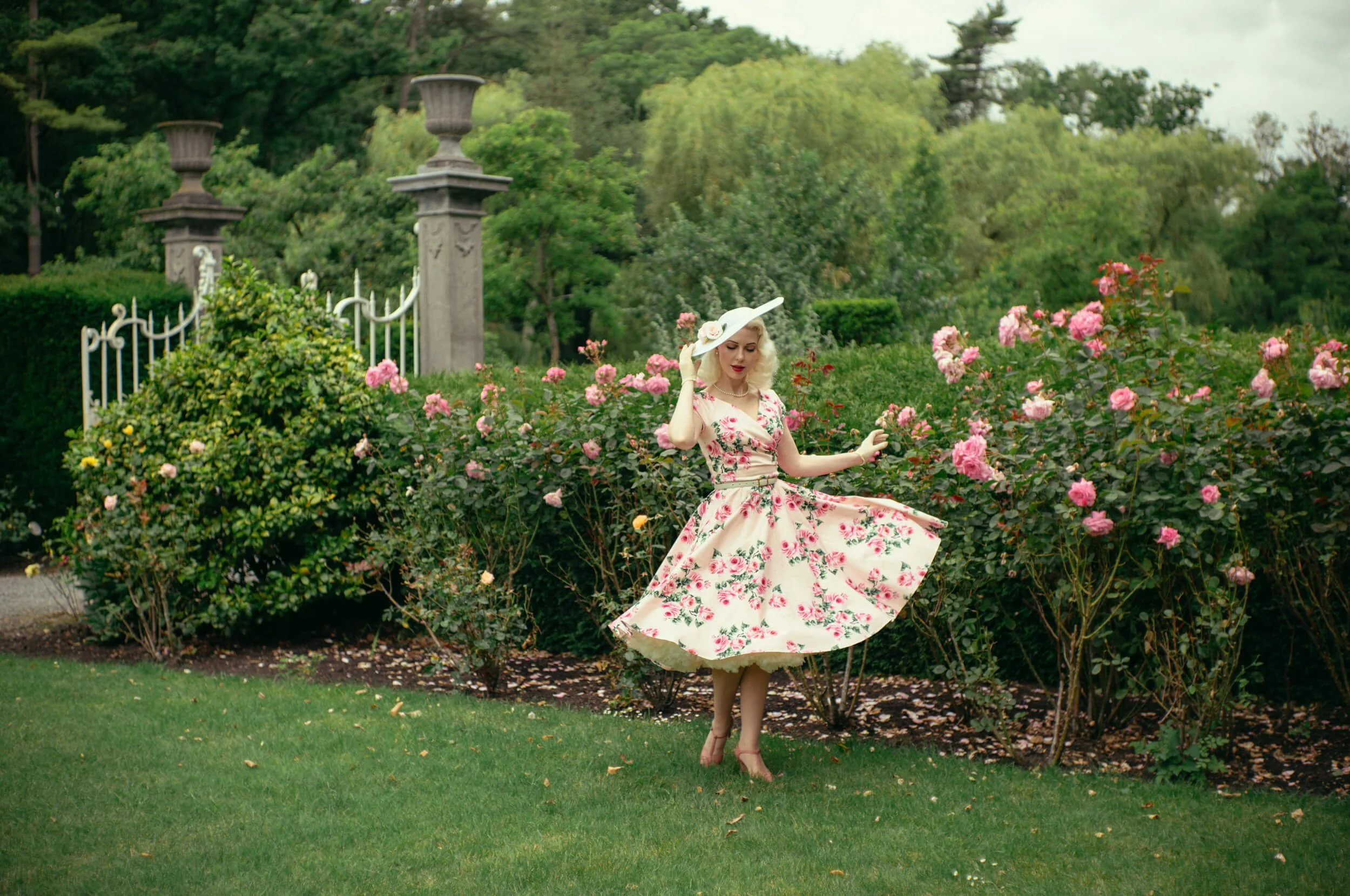 Full-body portrait of Yulia photographed with the Light Lens Lab 50mm f/1.9 Rigid-ZS6 in a rose garden, demonstrating the lens's three-dimensional rendering, subject separation and vintage character.
