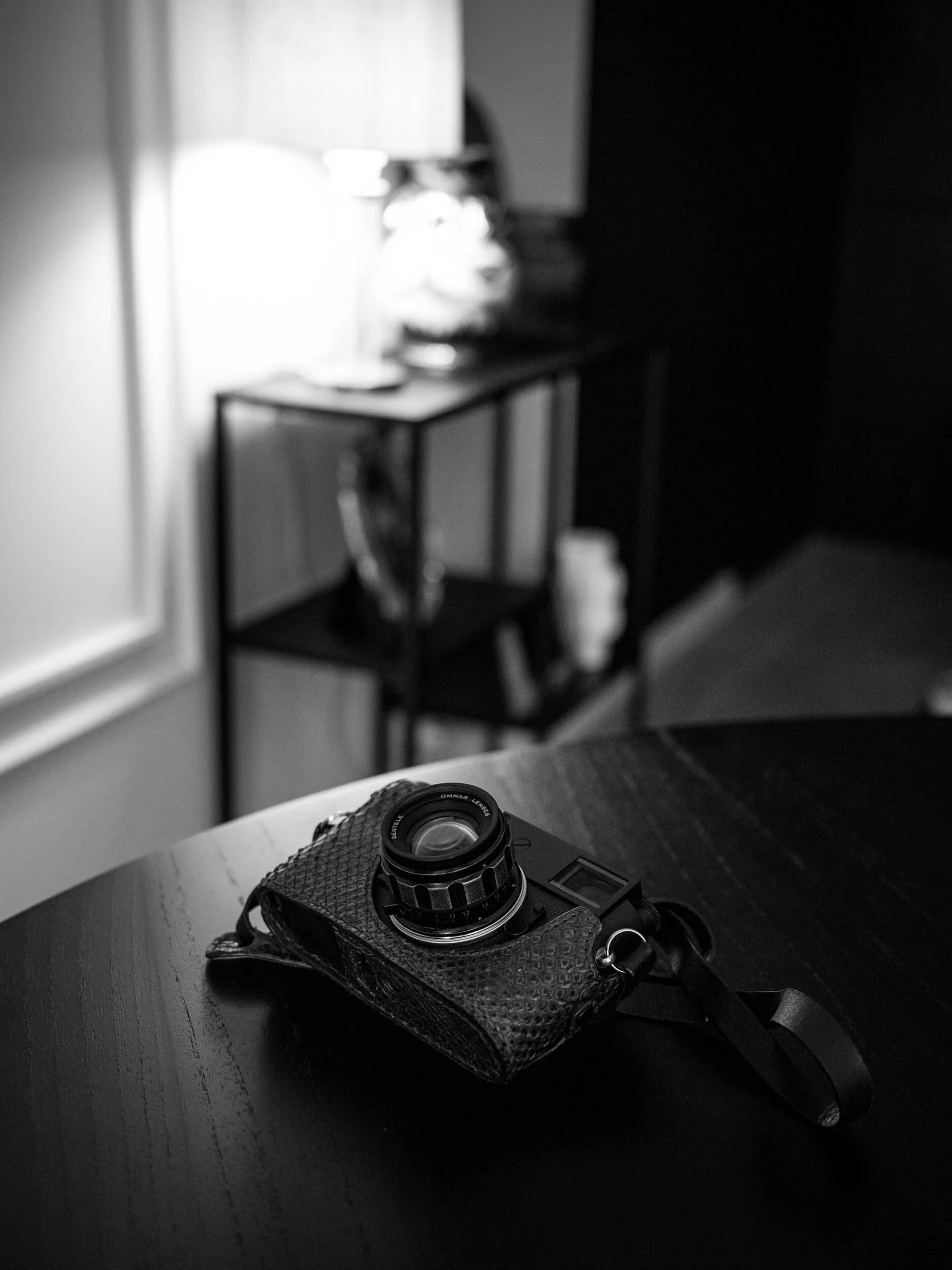 Omnar Bertele 50mm f/2 mounted on a Leica M11 Monochrom resting on a dark wooden table