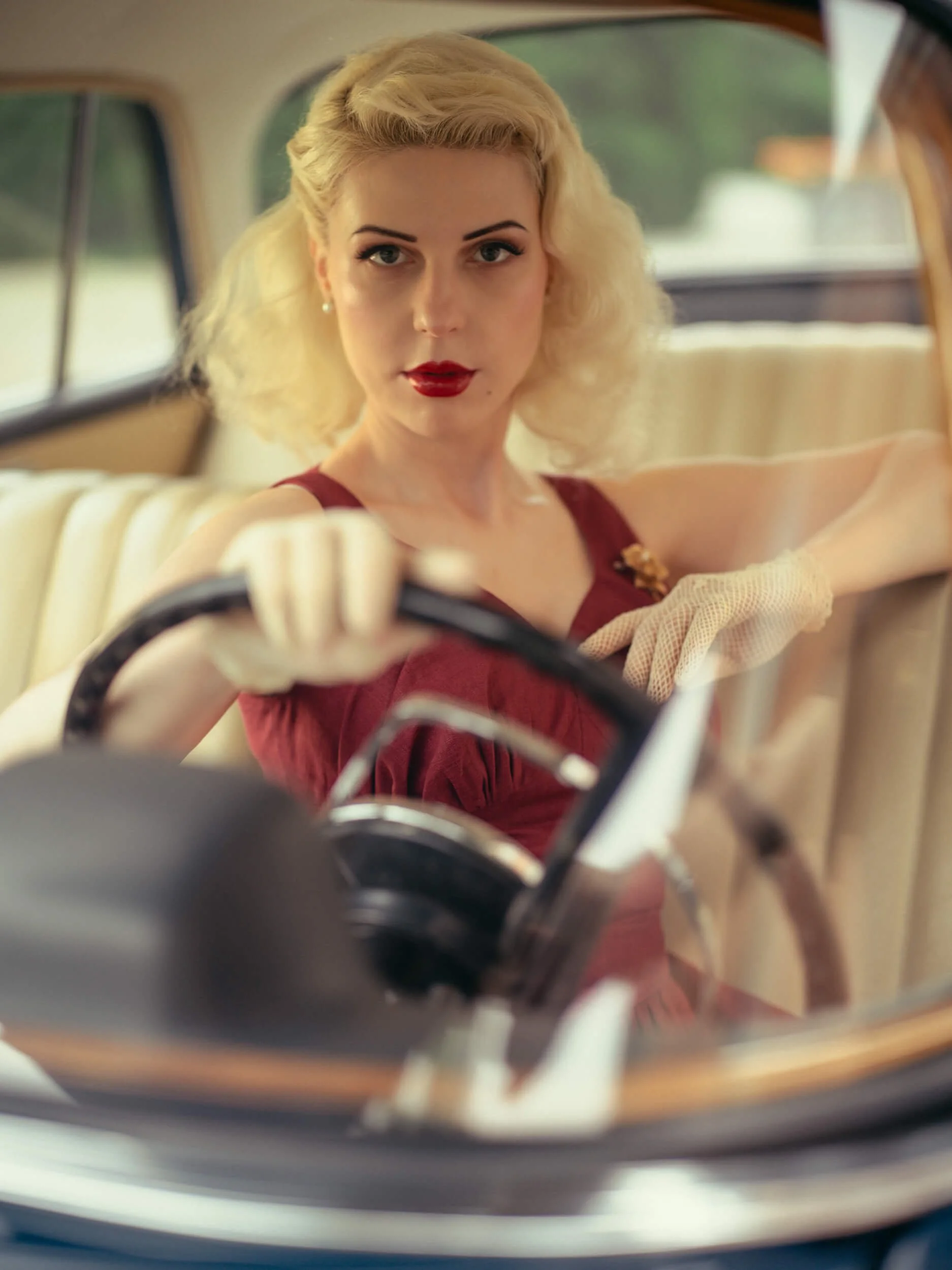 Yulia in a red dress sitting inside a vintage Mercedes-Benz 220