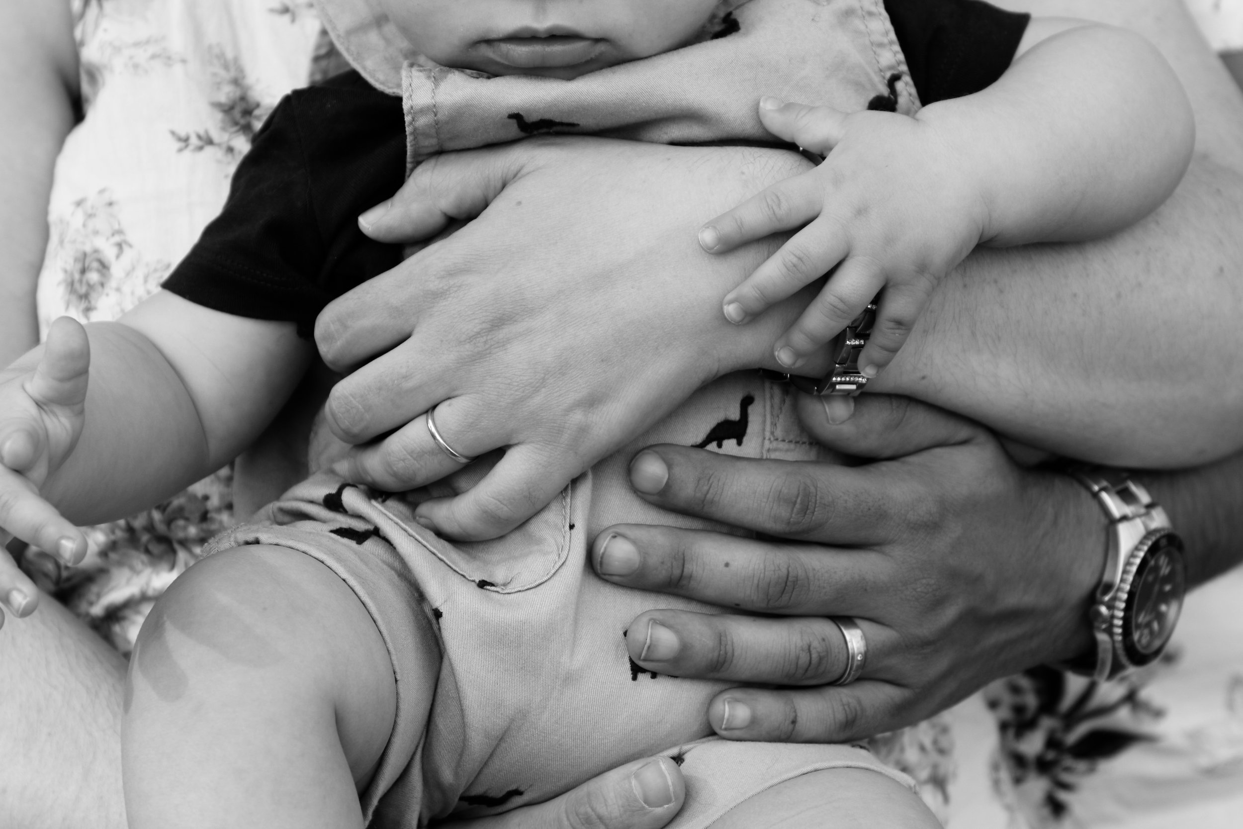 Black and white photo of a child's hands resting on an adult's arms.