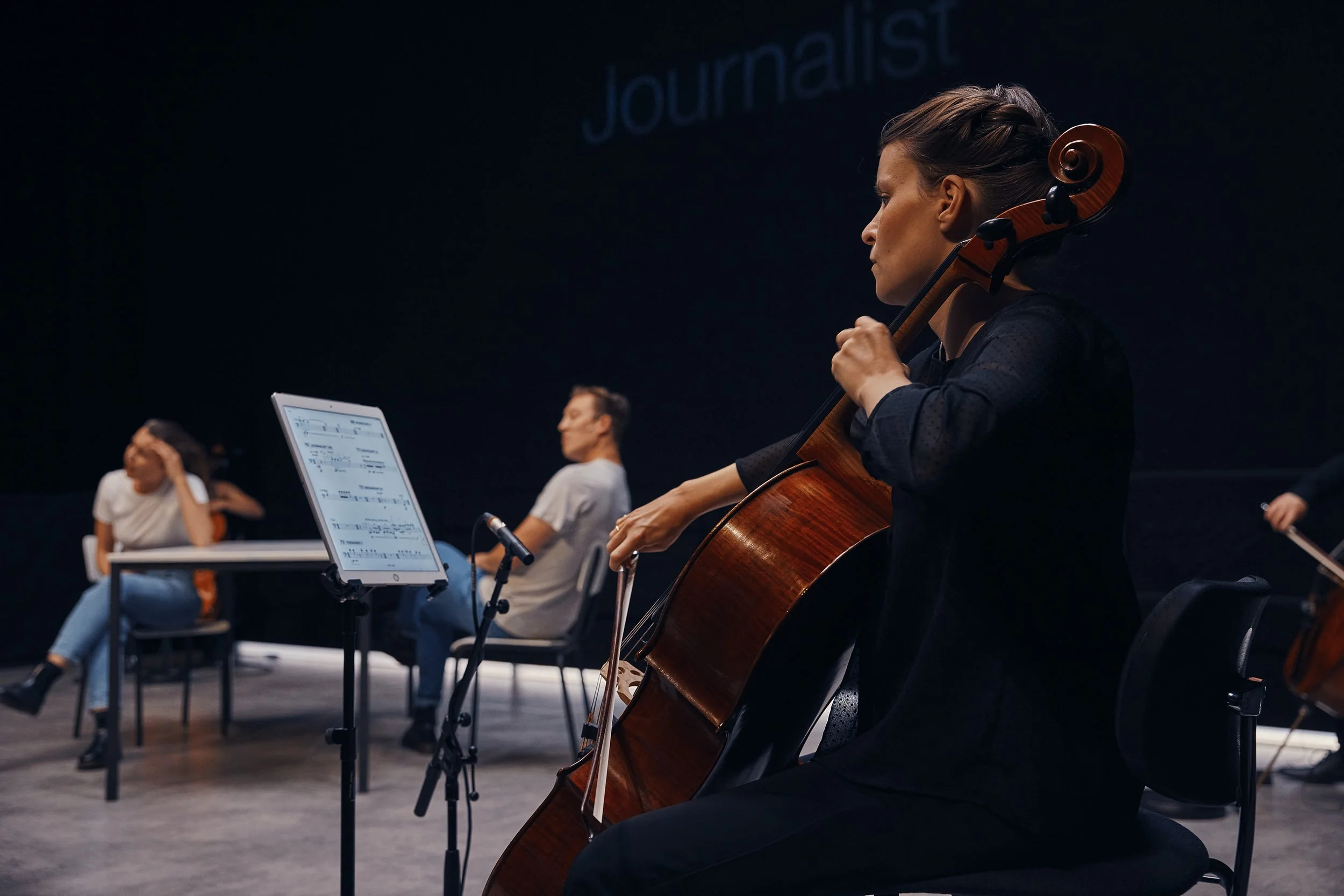 Musicians practicing with cellos and sheet music in a studio setting.