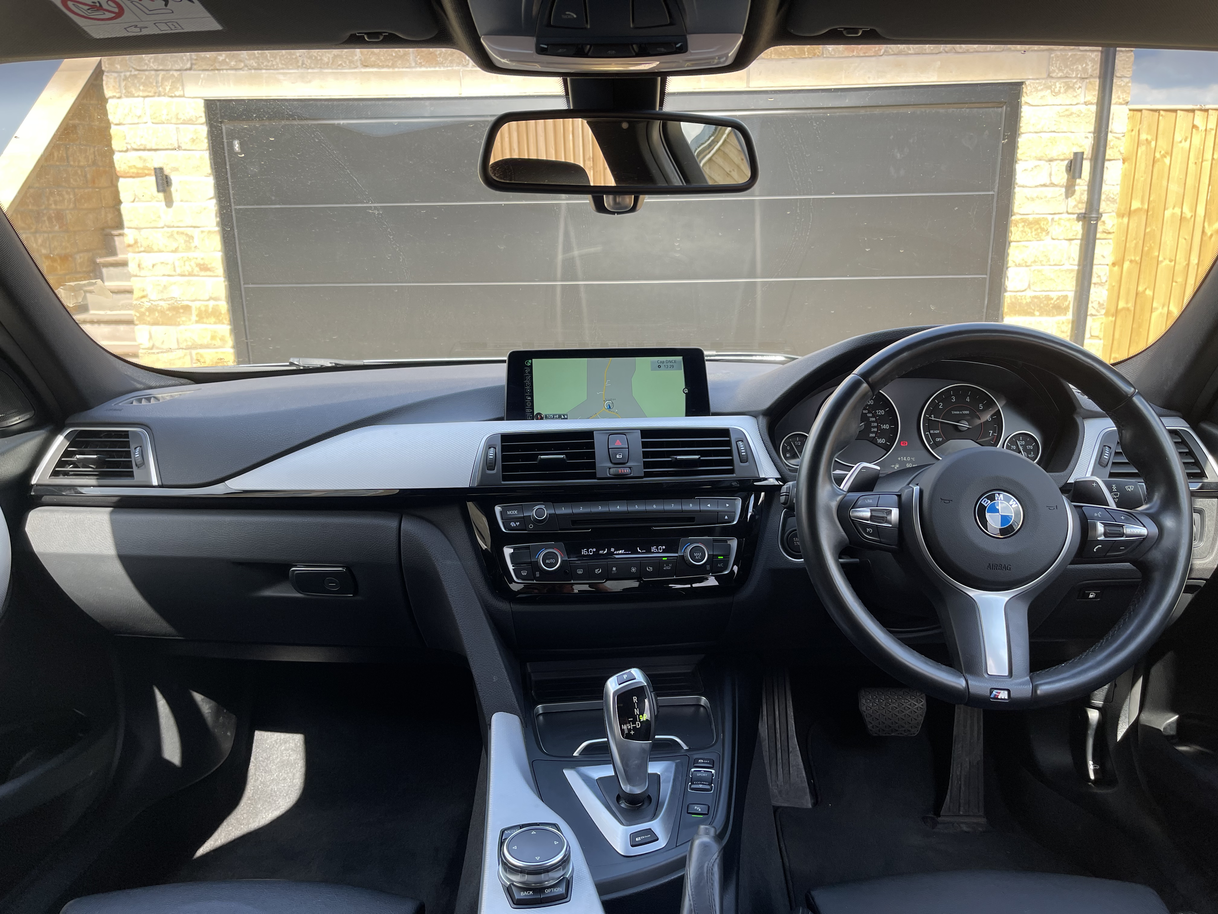 Interior of a BMW car showing the steering wheel, dashboard, and navigation screen.