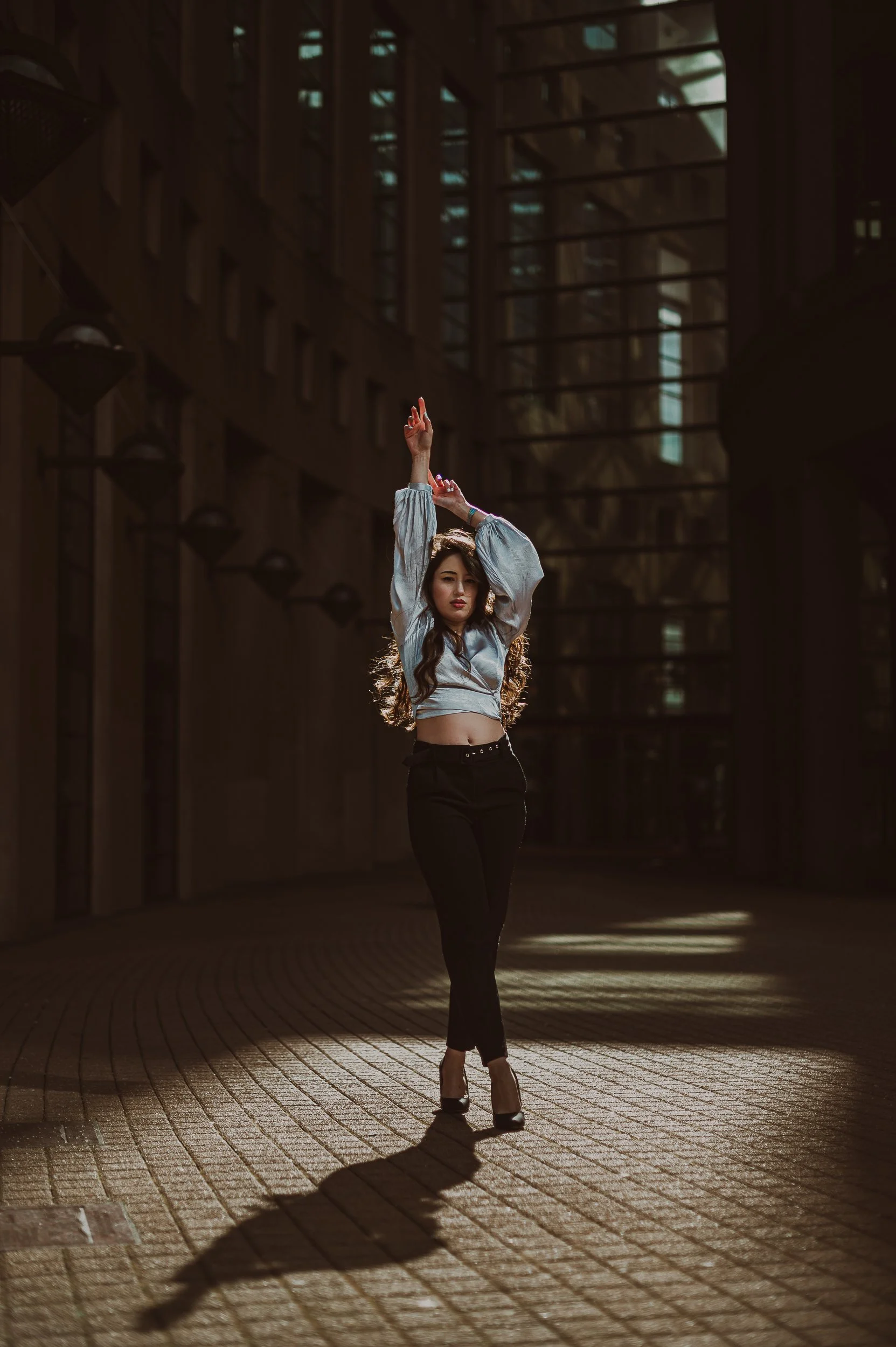 Femme dans une tenue chic posant dans un espace architectural en bois avec lumière naturelle à la bibliothèque de Vancouver.