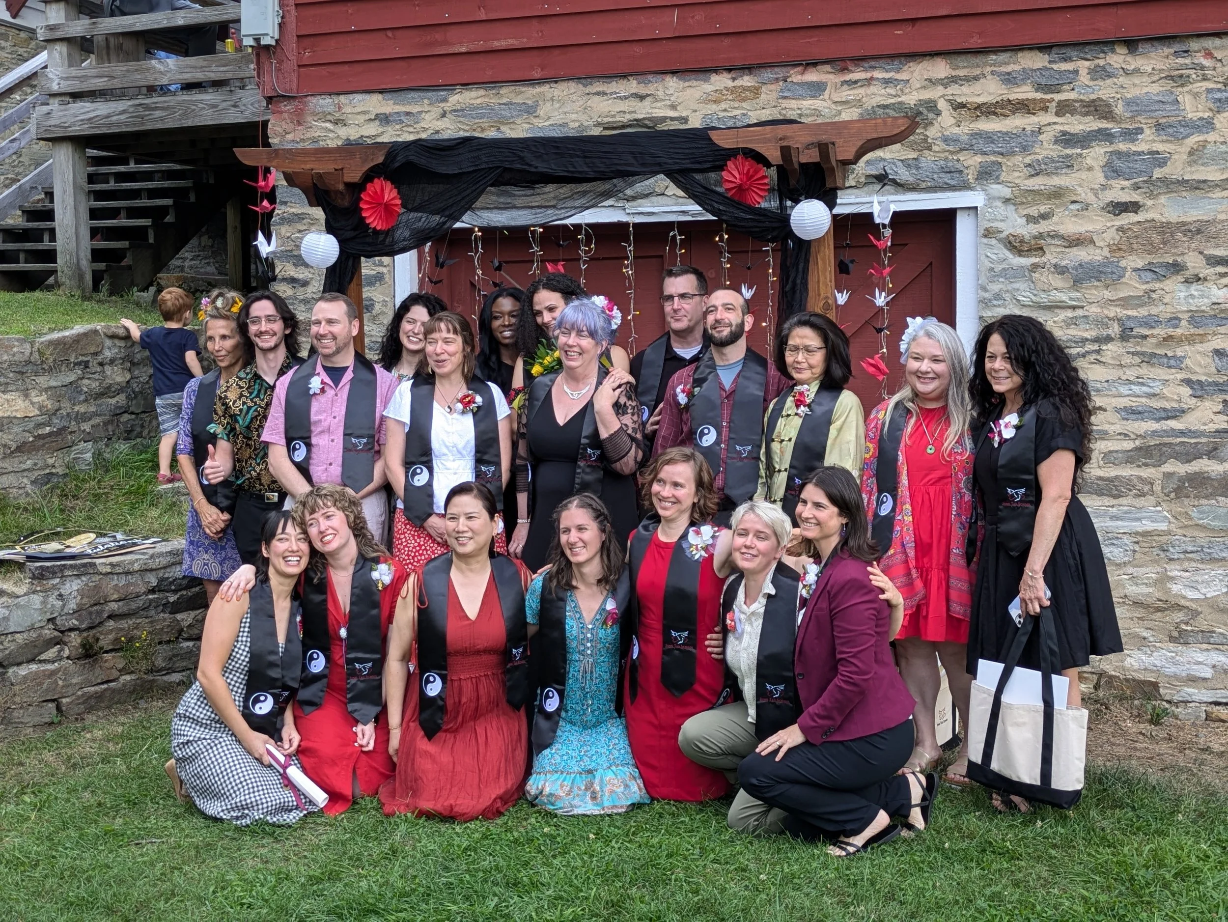 A photo showing a group of recent acupuncture school graduates under a decorated arch.