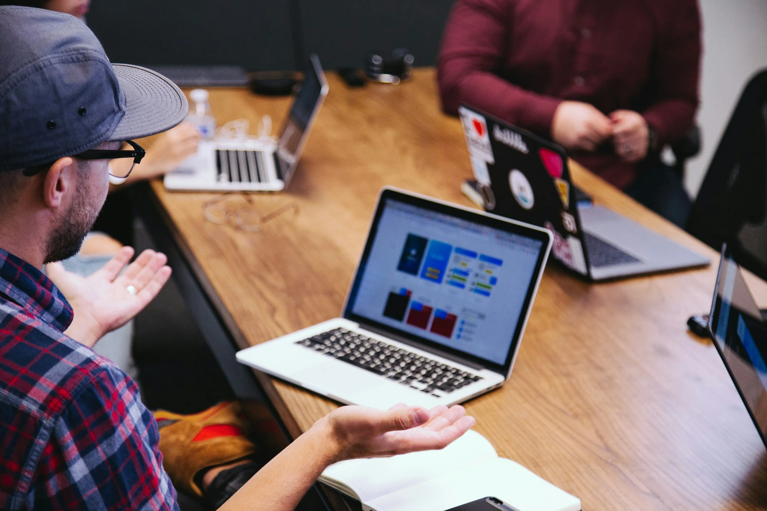 sales meeting with 3 attendees at a desk with their laptops