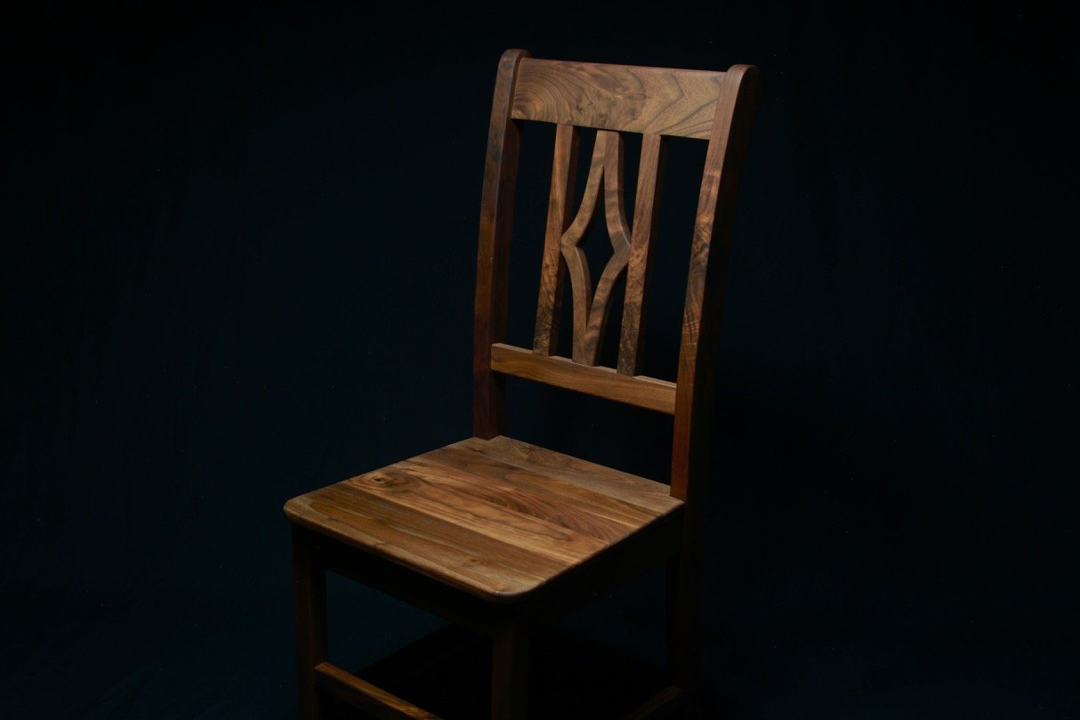 Custom built walnut wooden chair with carved star backrest on dark background