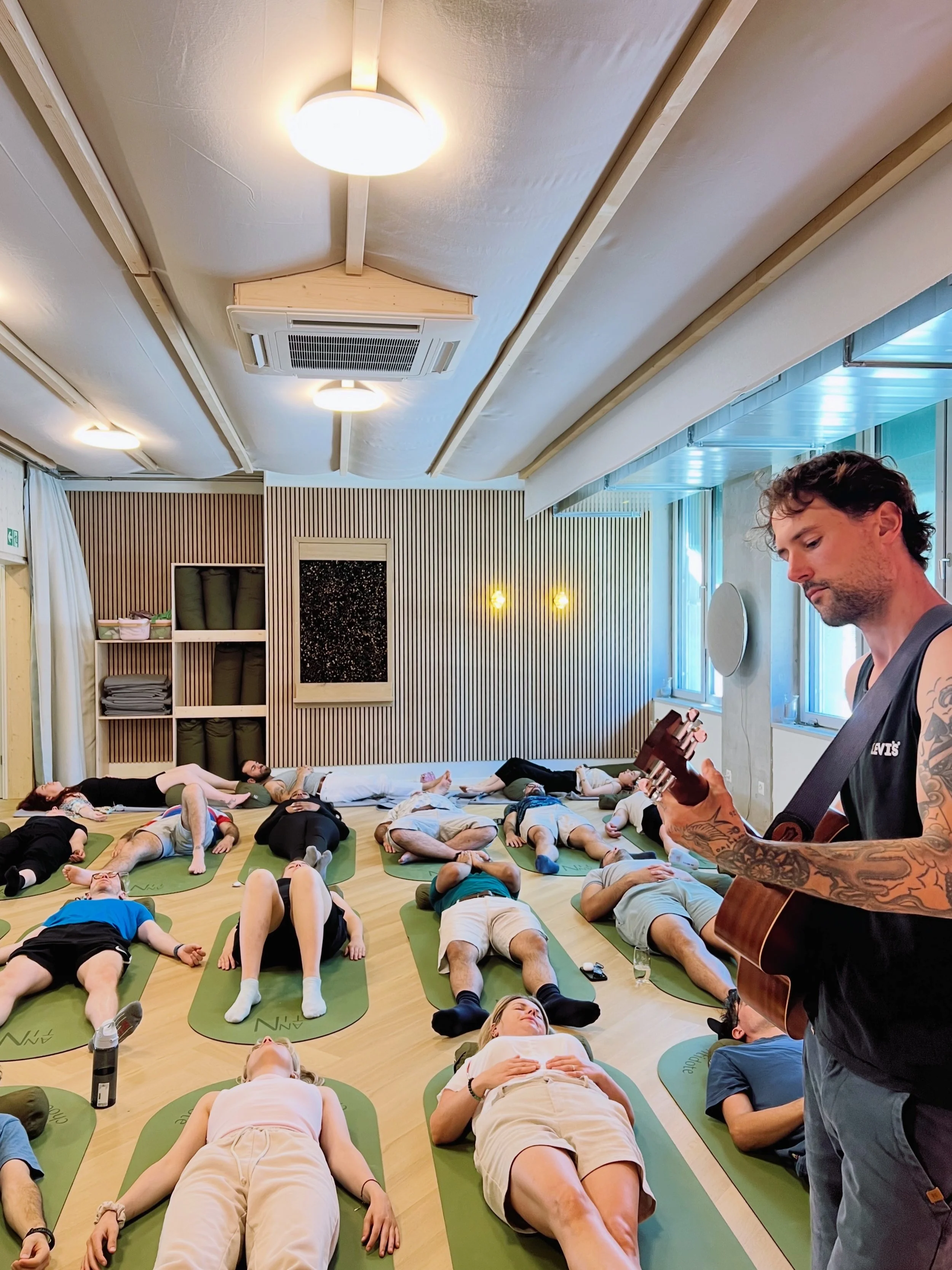 Participants resting during a breathwork journey with live acoustic guitar music at ANNTIN studio in Zurich Nord.