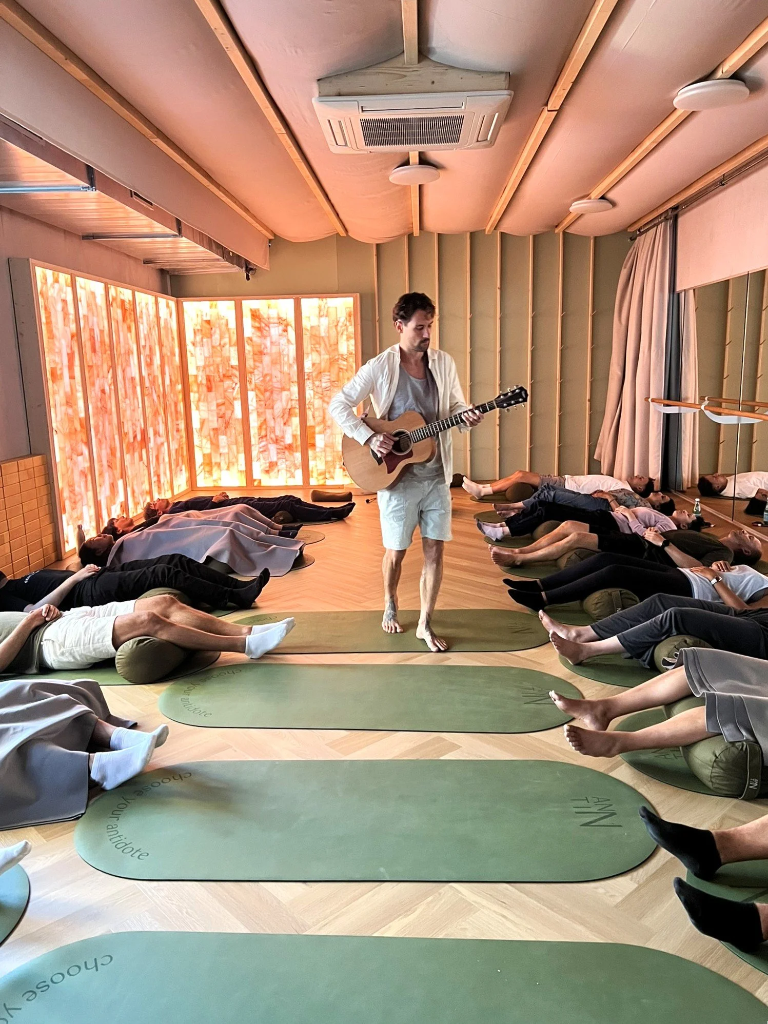 Certified instructor guiding a sound healing and breathwork experience with live guitar at ANNTIN studio.