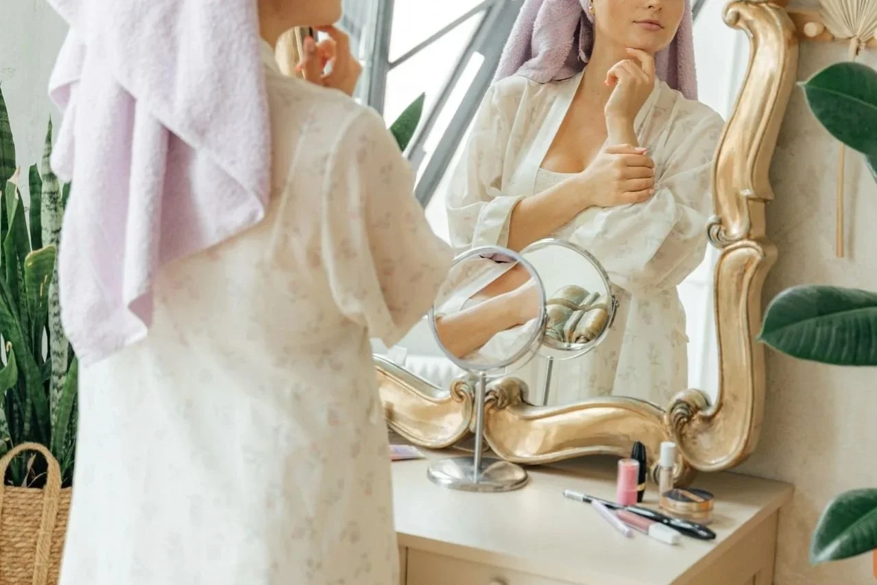 Thoughtful woman looking at herself in the mirror.