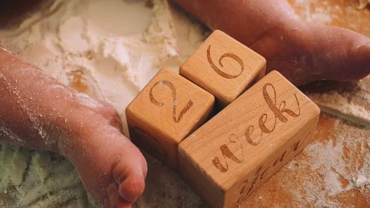 Wooden blocks displaying "9 week" beside baby feet