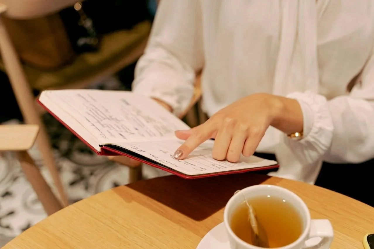Person reviewing a planner over tea