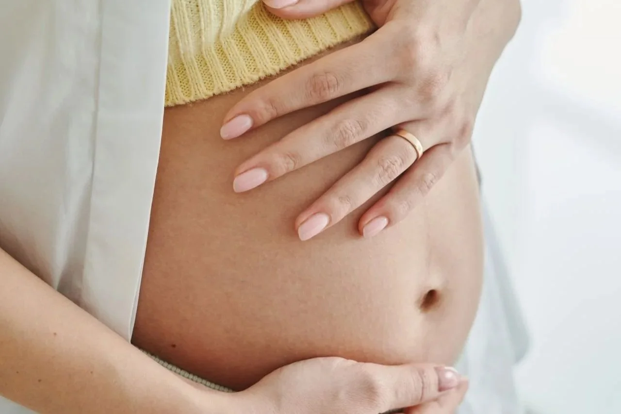 Pregnant woman gently holding her belly