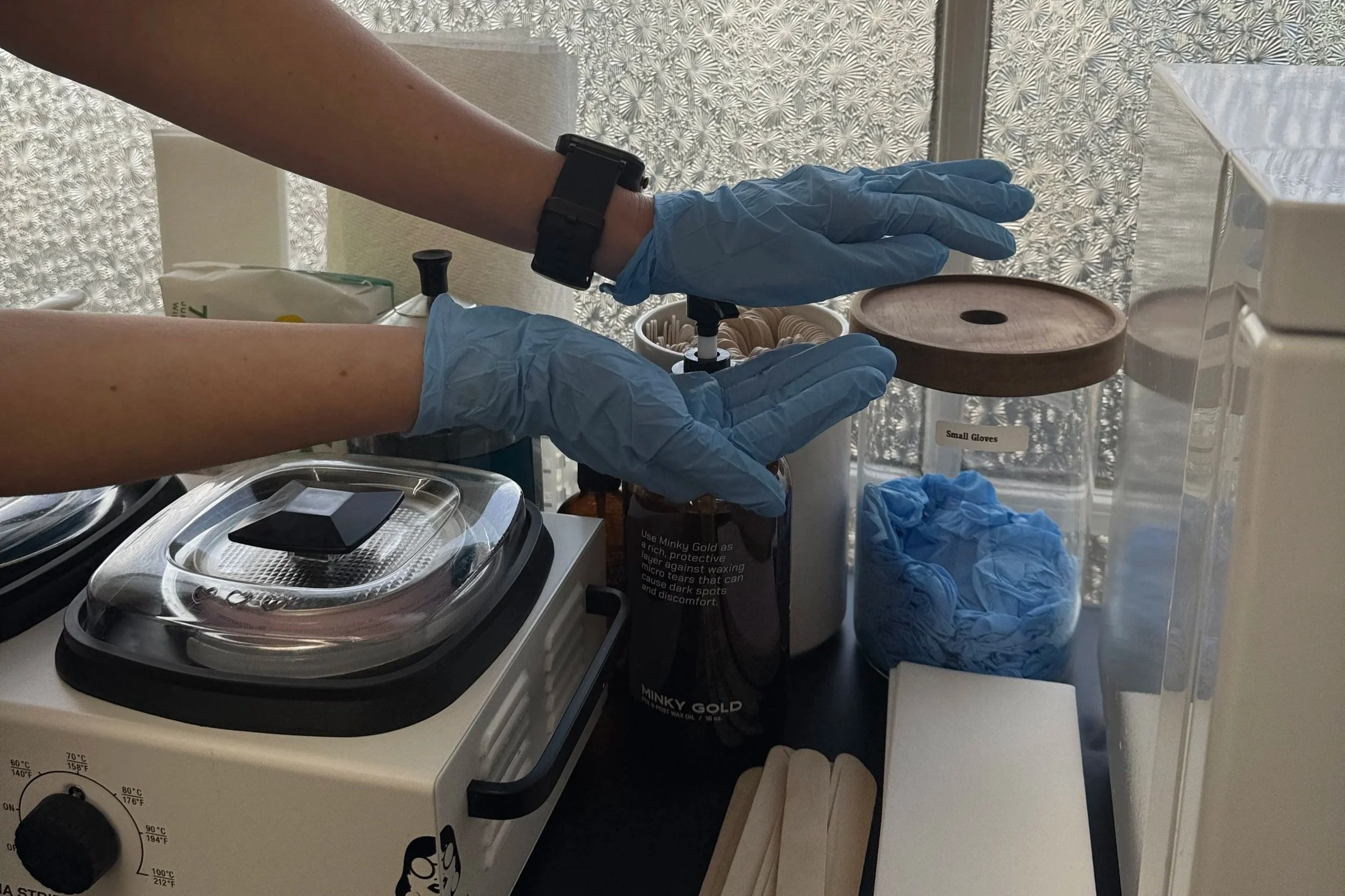Waxing professional wearing gloves and preparing wax
