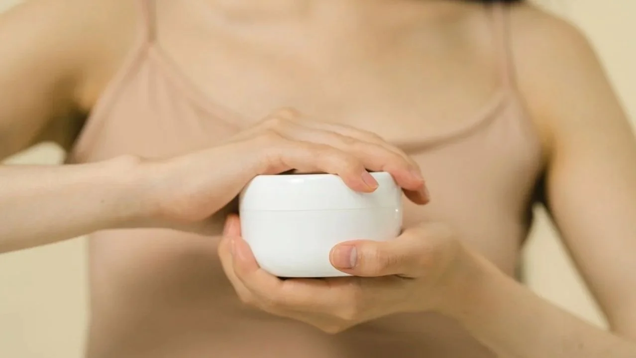 Person holding a moisturizer for underarm skin care after hair removal