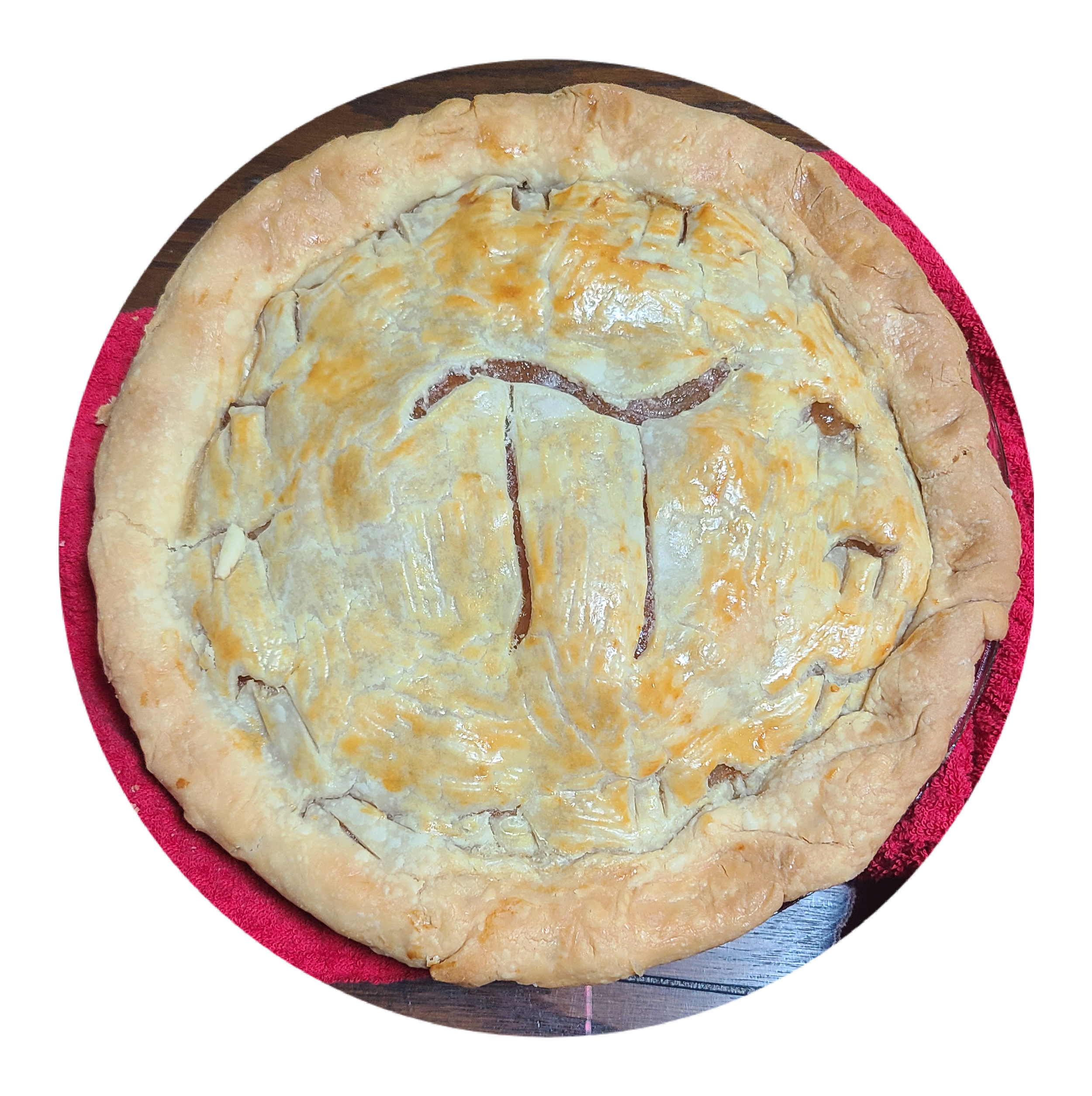 An apple pie with a golden, slightly brown crust showing the Greek symbol for Pi  sitting on a red cloth on a wooden surface.