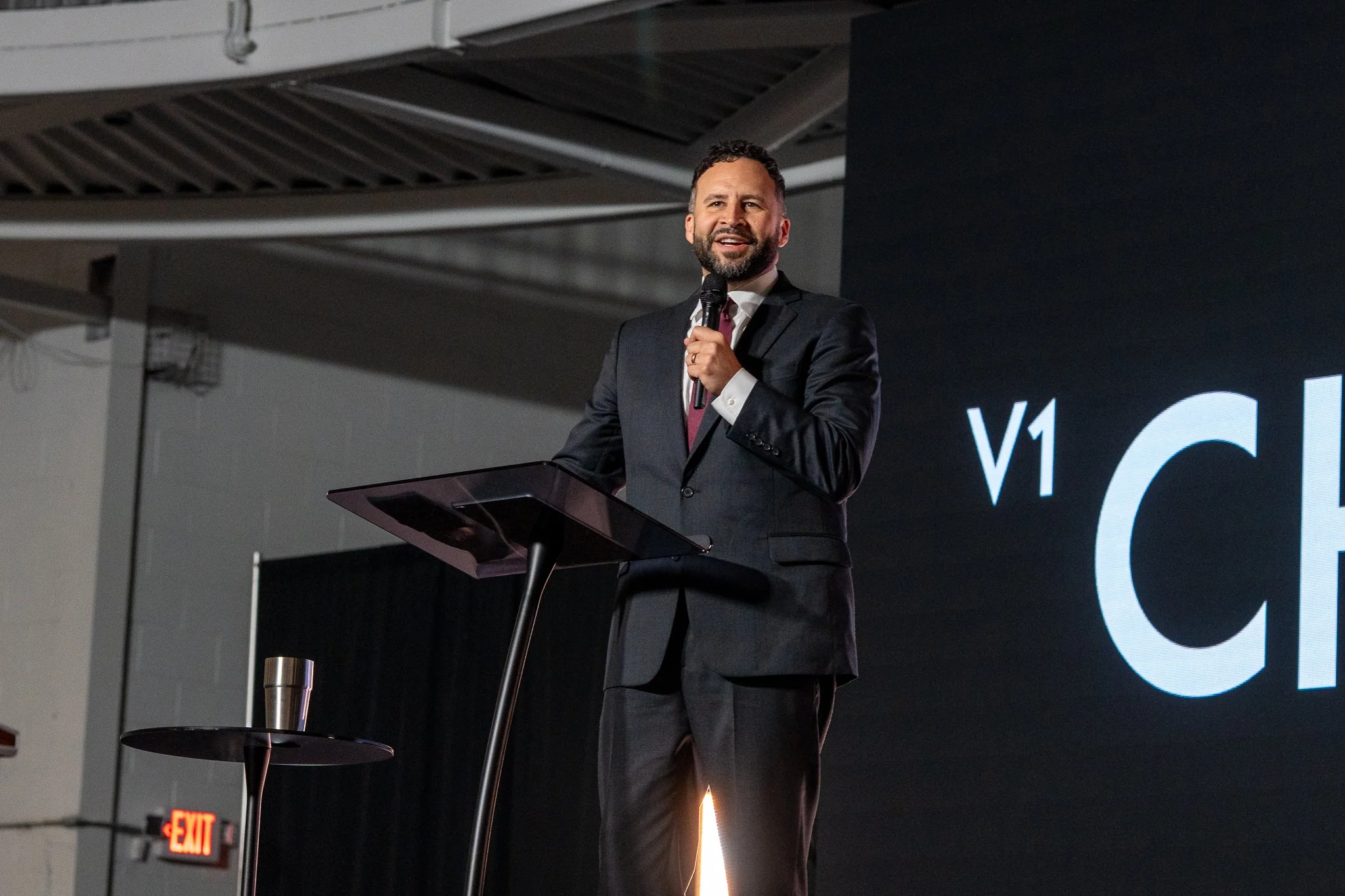 Mike Signorelli speaking into a microphone at a V1 Church podium.