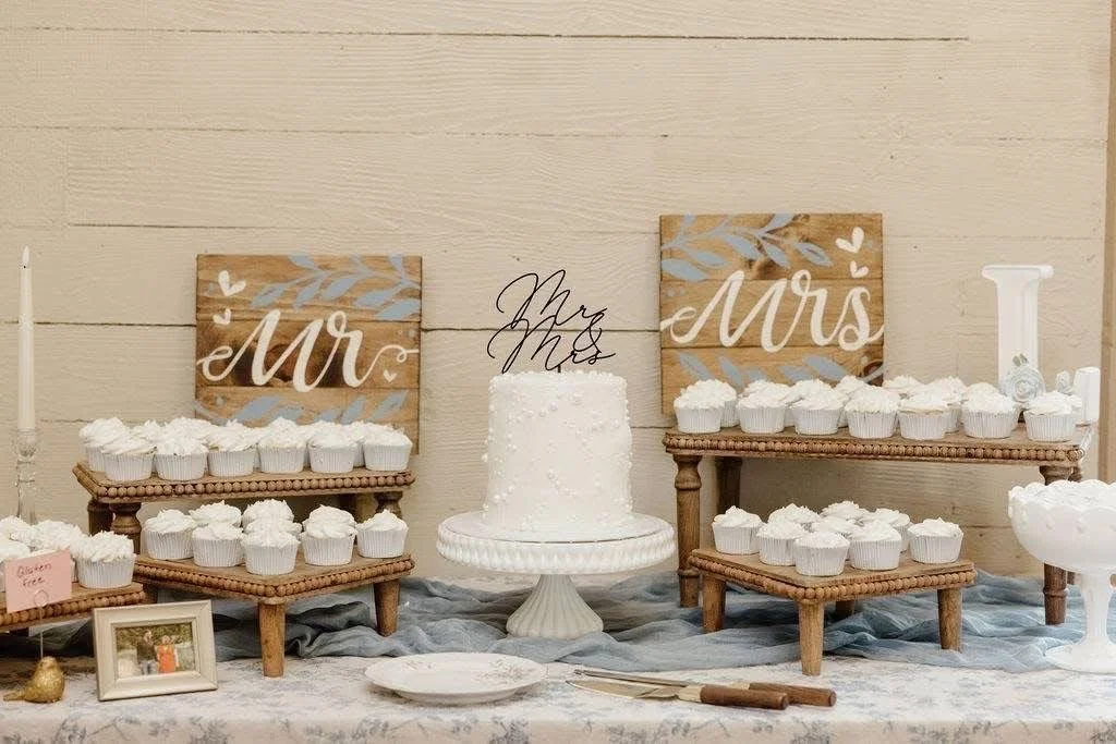 Wedding cake display with cupcakes, Mr. and Mrs. signs, and decorative elements.