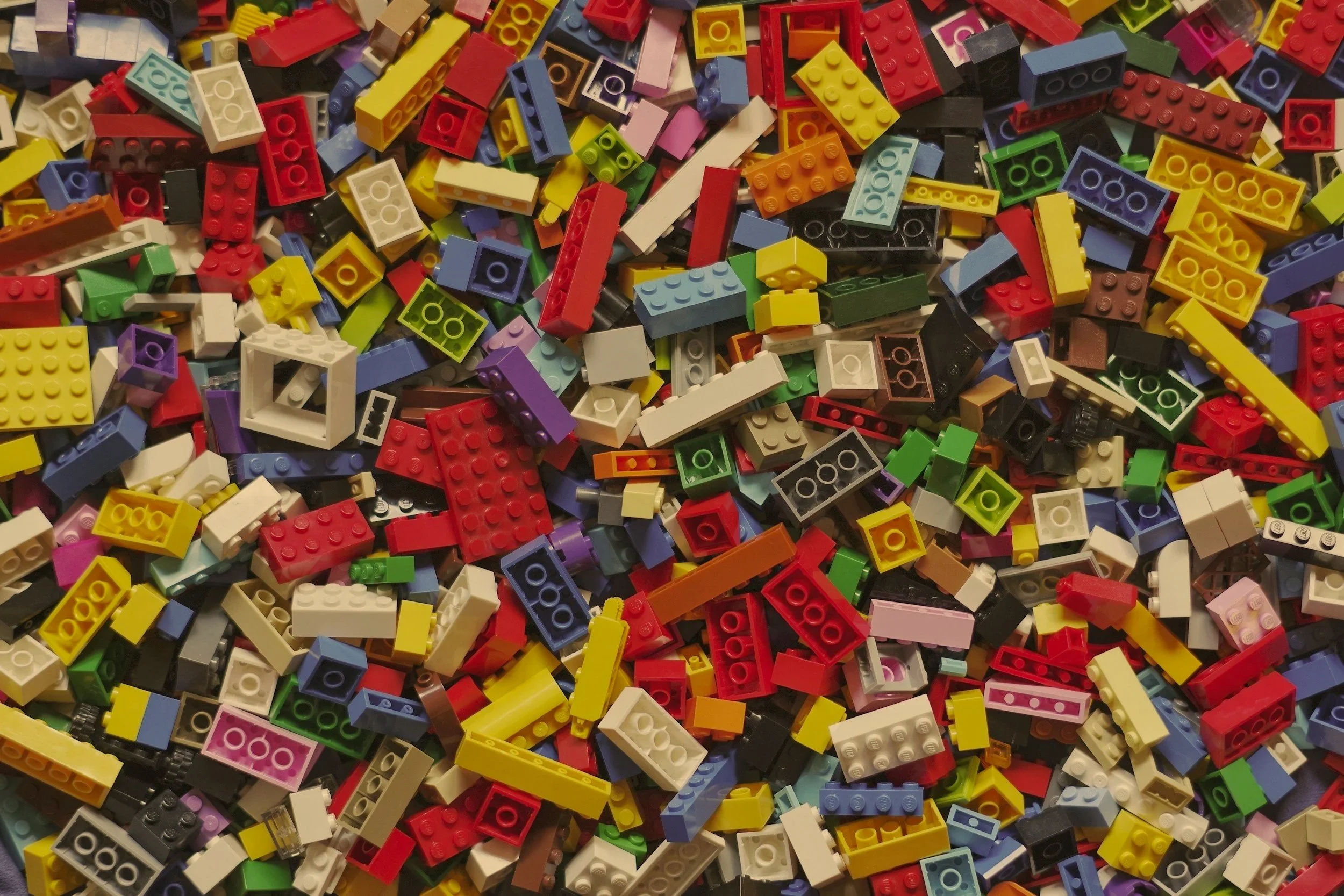 A large collection of colorful LEGO bricks and pieces scattered all over.