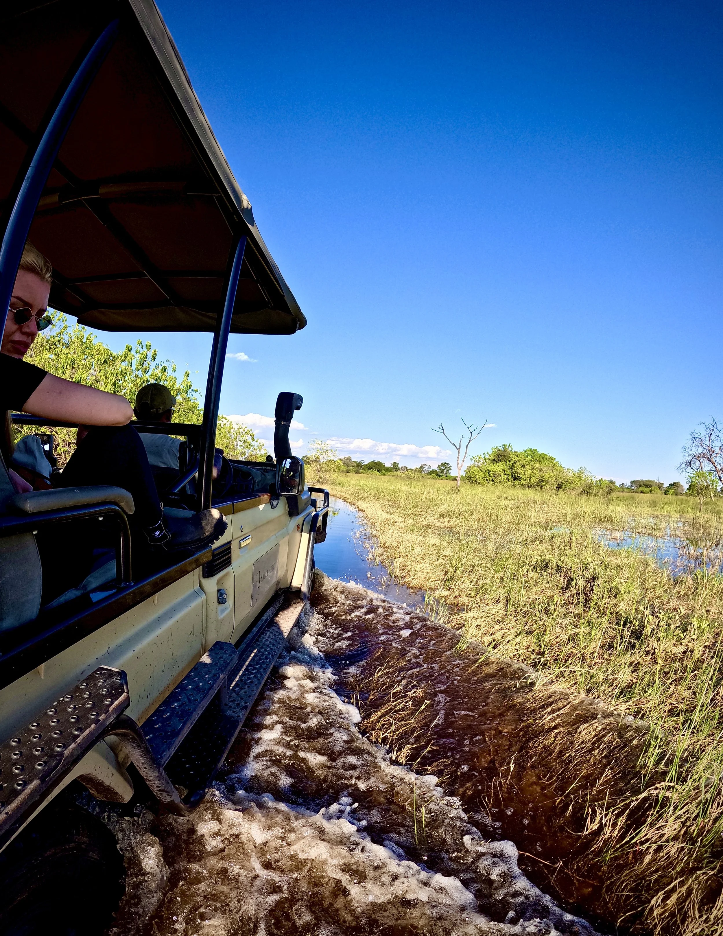 Safari vehicle crossing flooded tracks in Khwai Private Reserve