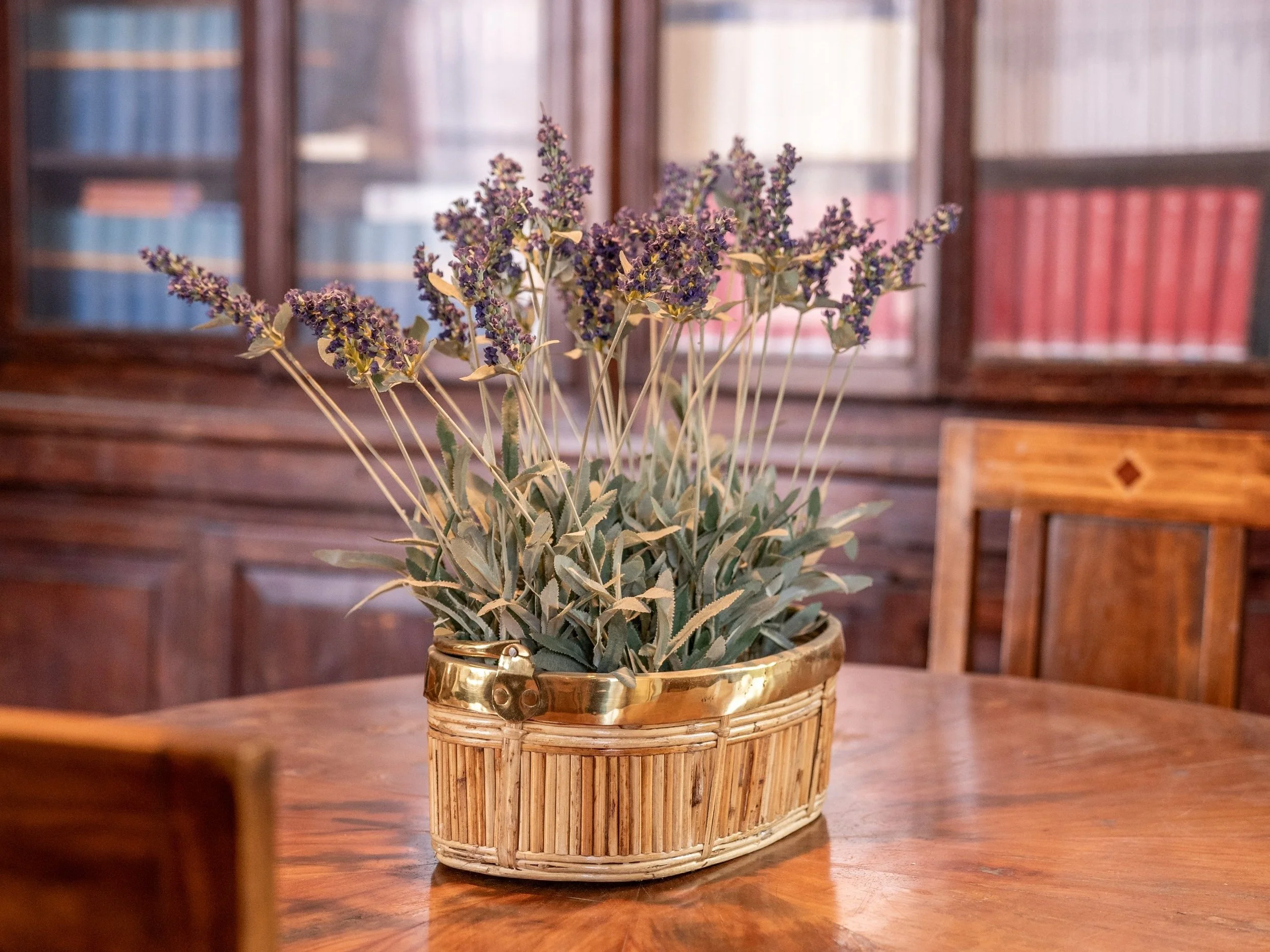 Vaso con fiori di lavanda su un tavolo di legno, sfondo di mobili antichi.
