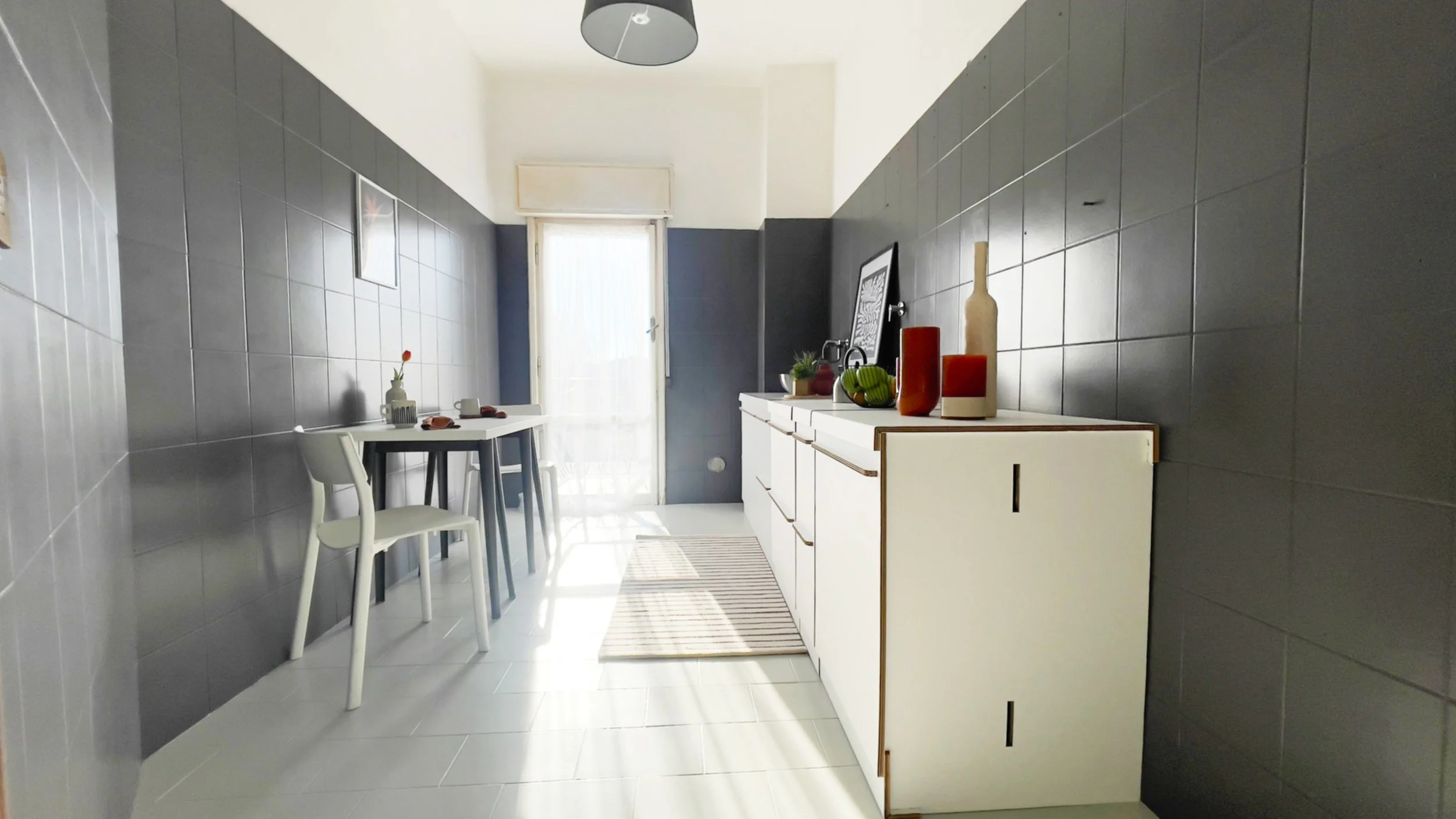 Cucina moderna con mobili bianchi, tavolo con sedie e finestre con tende, piastrelle grigie.