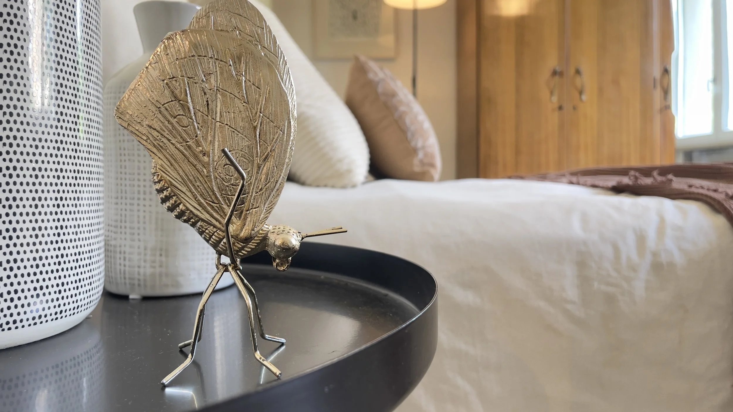 Decorazione dorata a forma di insetto su un tavolo nero in una camera da letto moderna.
