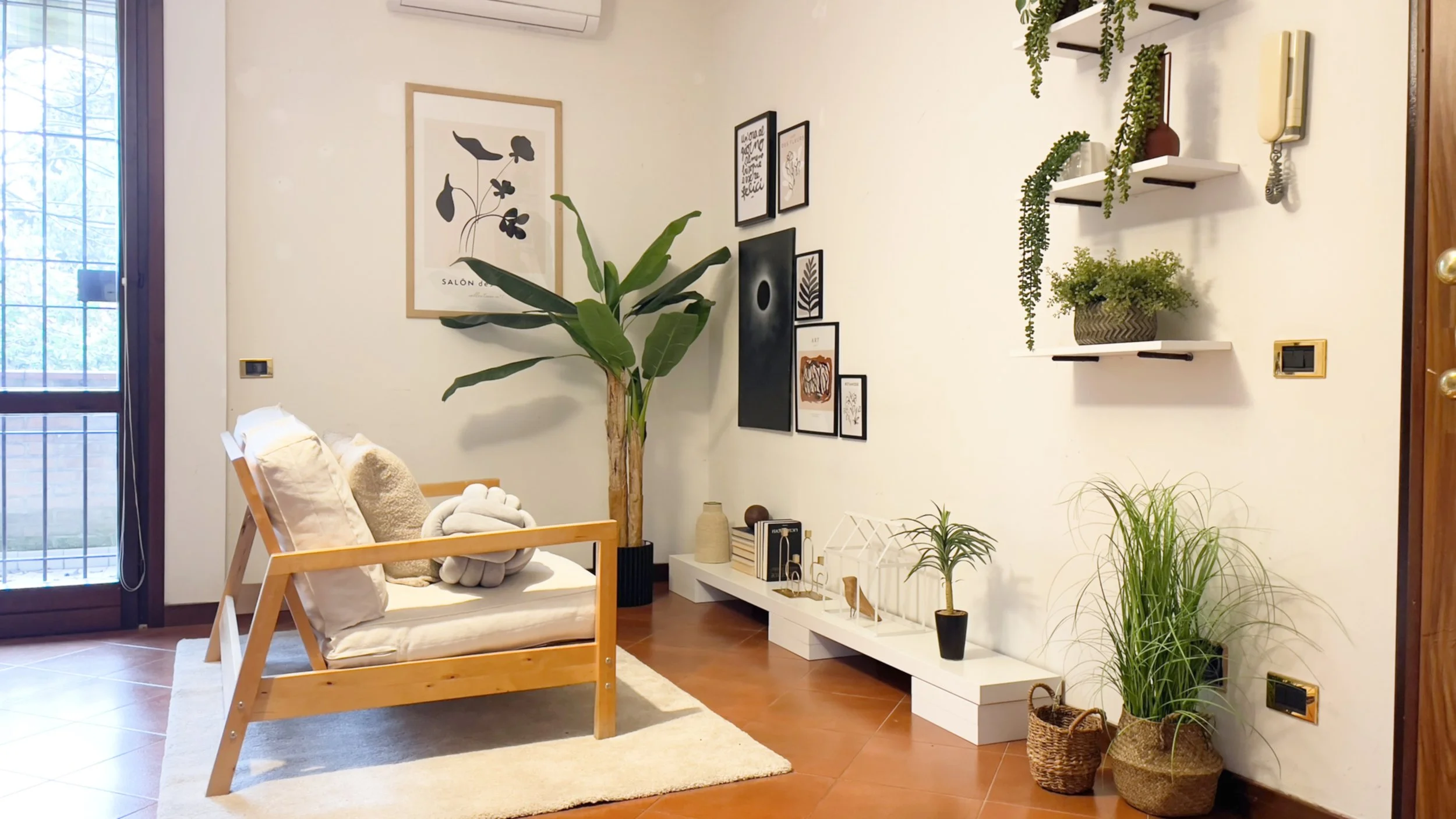 Soggiorno moderno con divano in legno, cuscini chiari, piante decorative, mensole con piante sospese e quadri alle pareti.