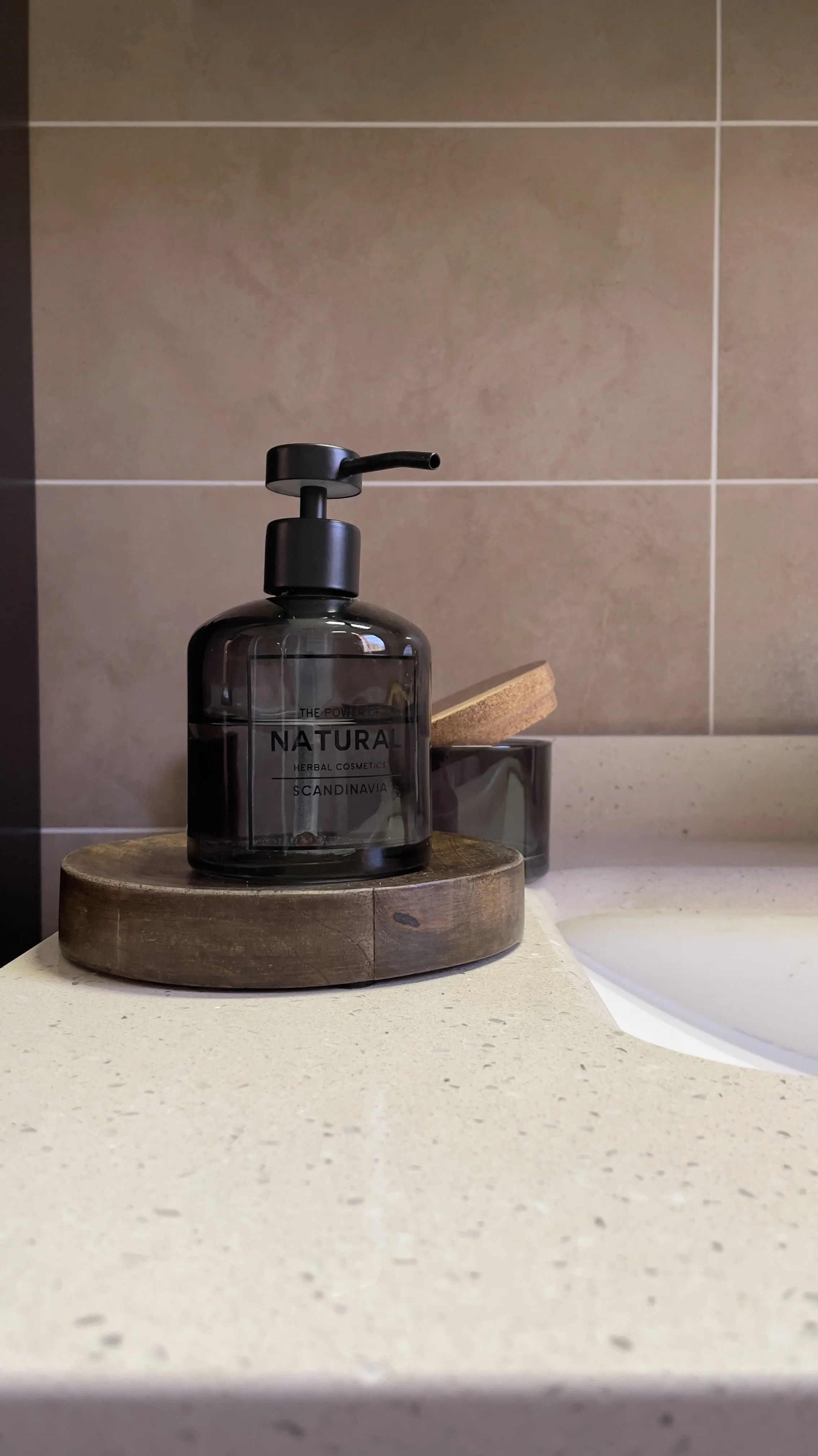 Dispenser di sapone nero su un ripiano di un bagno.