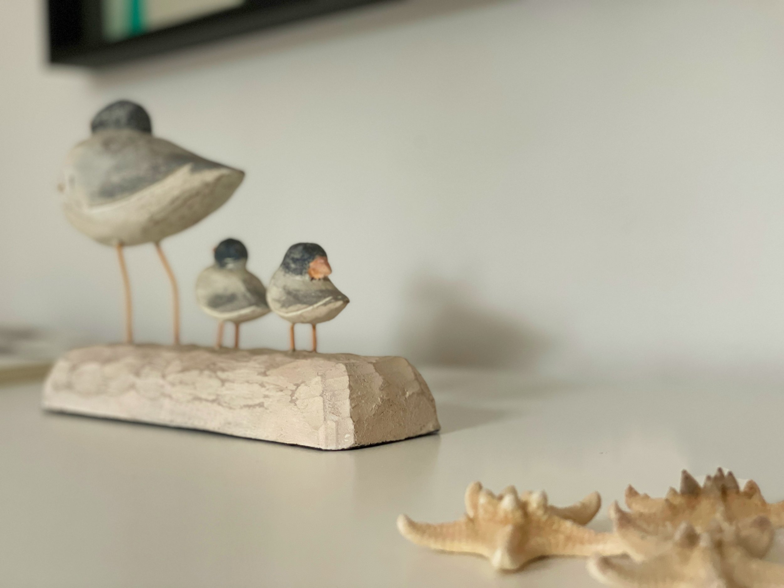 Scultura di uccelli in legno con stelle marine su una superficie bianca.