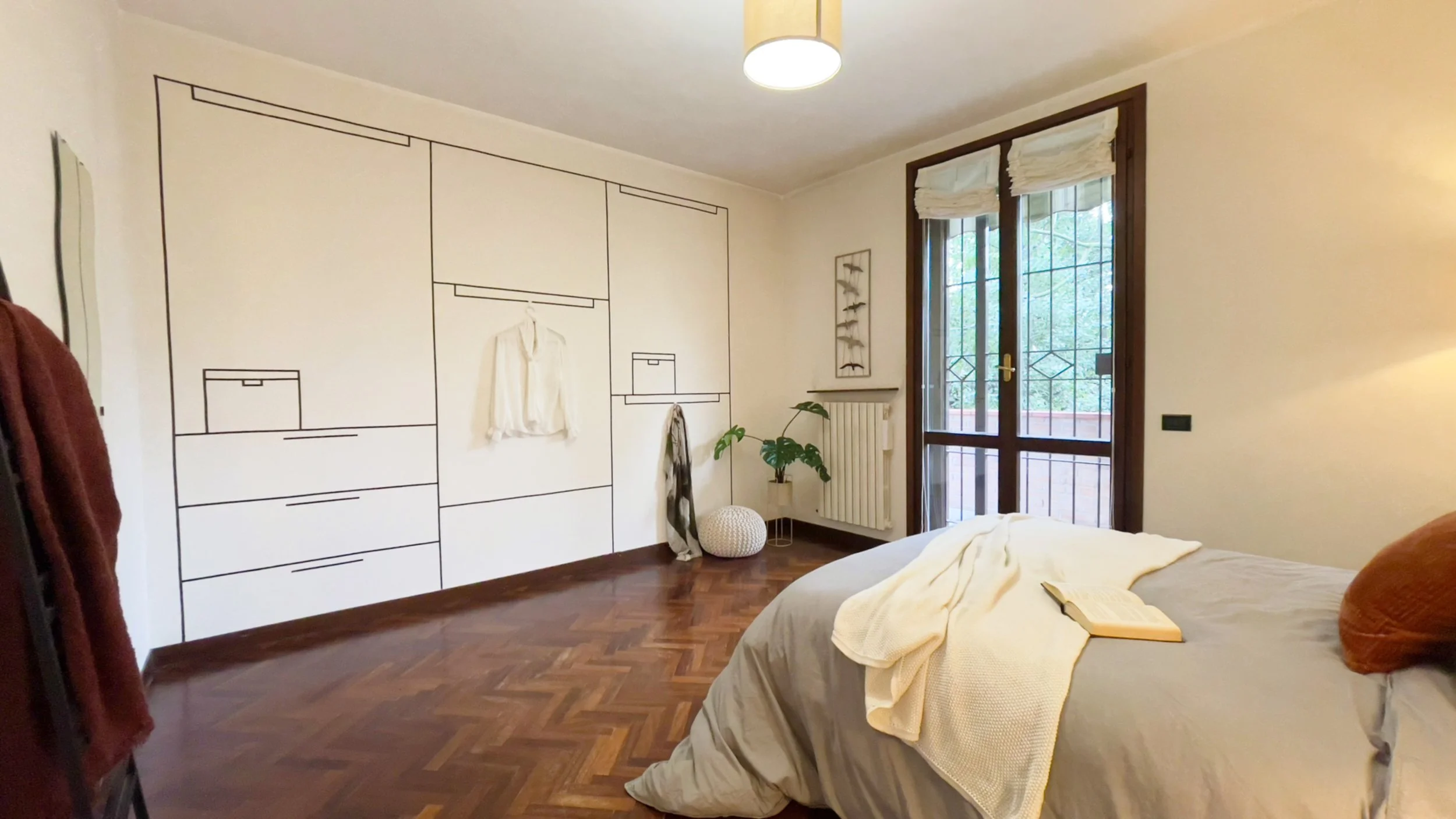 Camera da letto con disegno di armadio sulla parete, letto con coperta bianca, finestra con tende, pianta in vaso e lampada a sospensione.