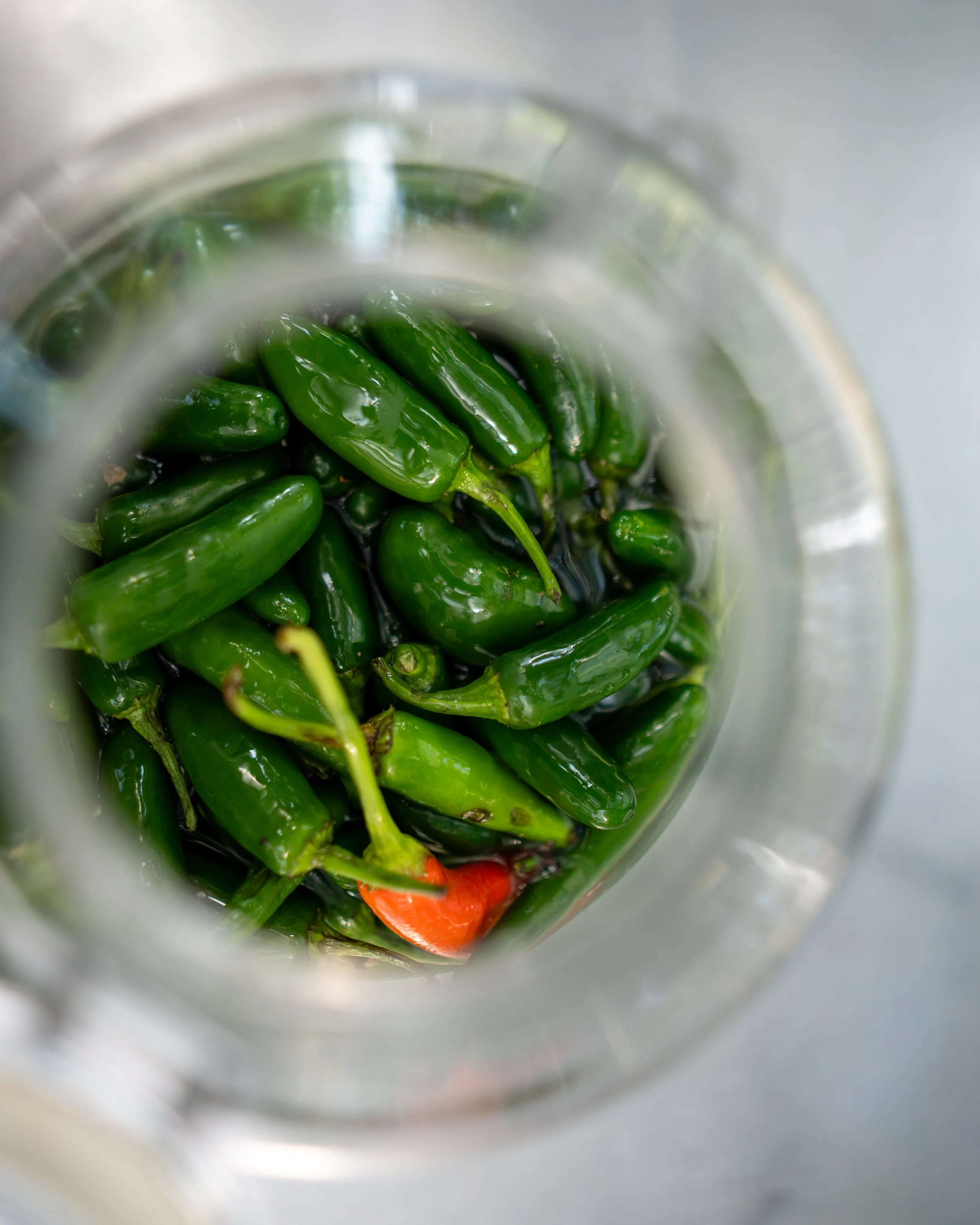 Green chili peppers inside a glass jar