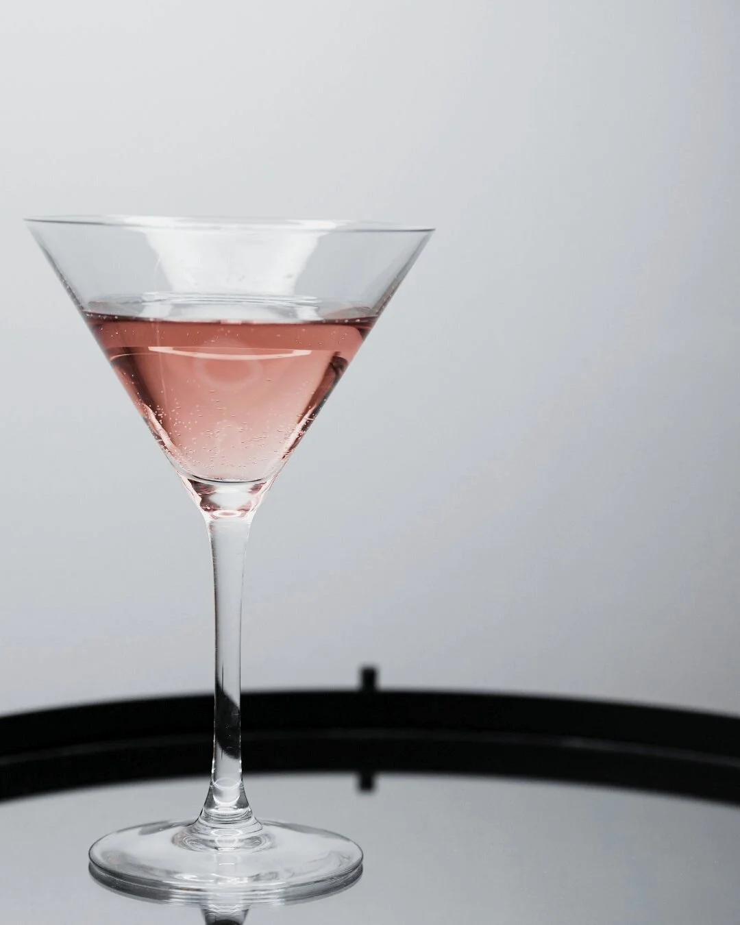 Cocktail glass with pink liquor served on a silver tray, evoking private concierge service and refined personal attention