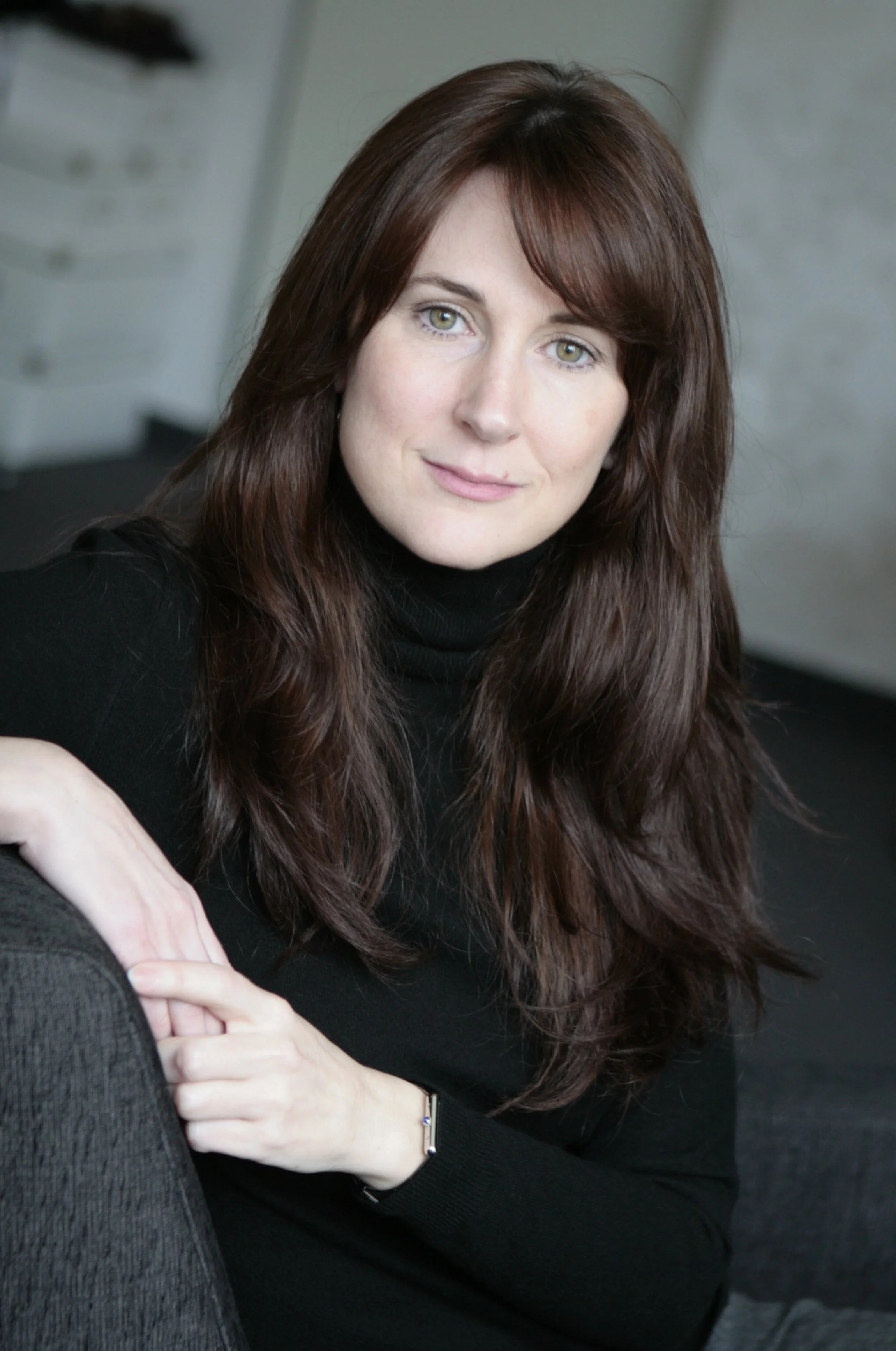 Zita Pavláth seated on a white chair, showcasing elegance and poise, representing luxury fashion consultancy