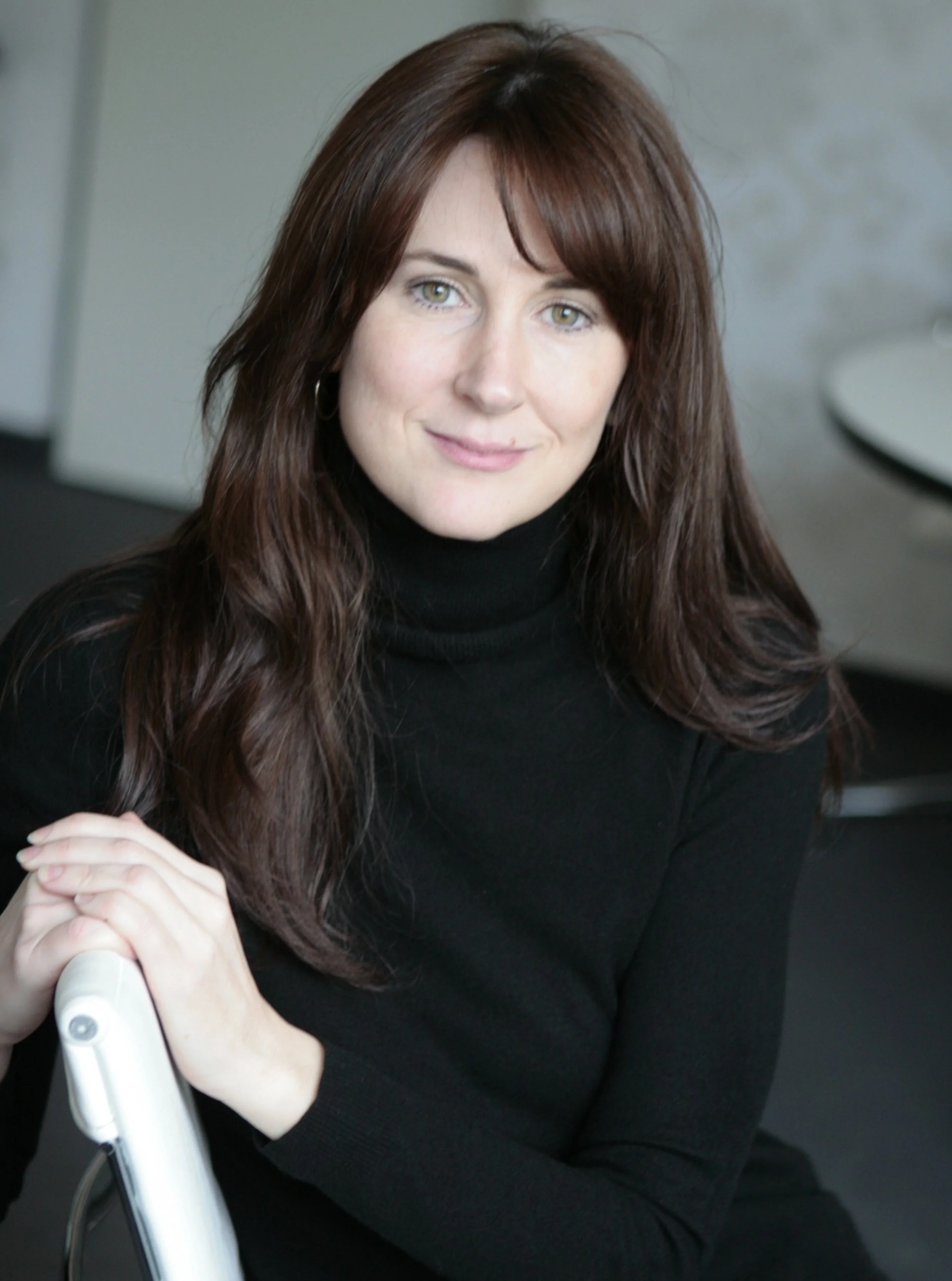 Zita Pavláth seated on a white chair, showcasing elegance and poise, representing luxury fashion consultancy